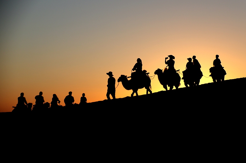 Visitors enjoy beautiful views of dusk at the Mingsha Mountain and Crescent Spring scenic spot in Dunhuang City, Gansu Province, August 9, 2024. /CFP