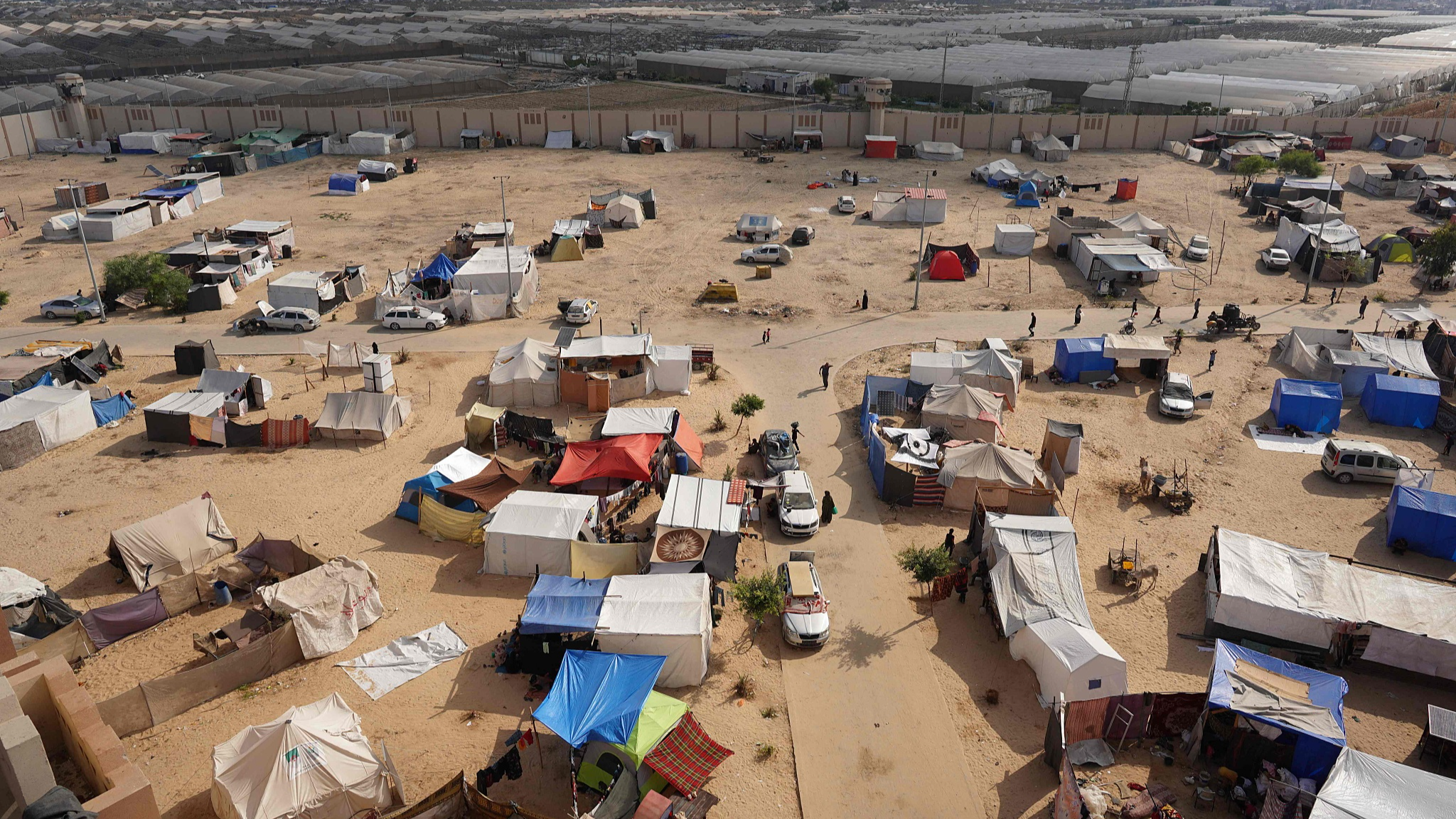 Palestinians walk near tents in the yard of the Asdaa central prison facility which has become a shelter for displaced people in Khan Yunis in the southern Gaza Strip on August 14, 2024. /CFP