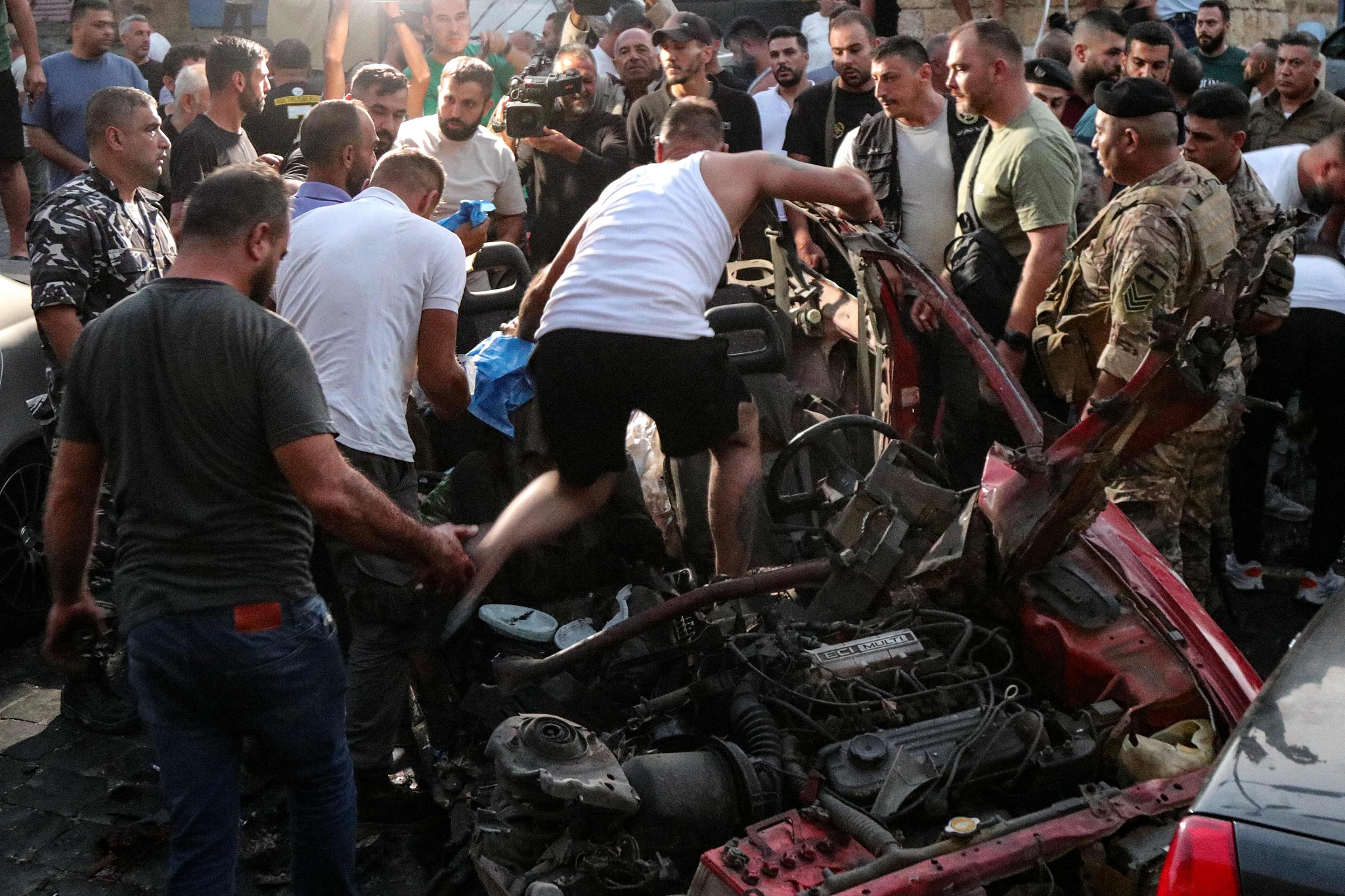 People and security forces check the wreckage of a car, reportedly targeted by an Israeli drone attack, in the main square of the southern Lebanese town of Marjayoun, August 14, 2024. /CFP