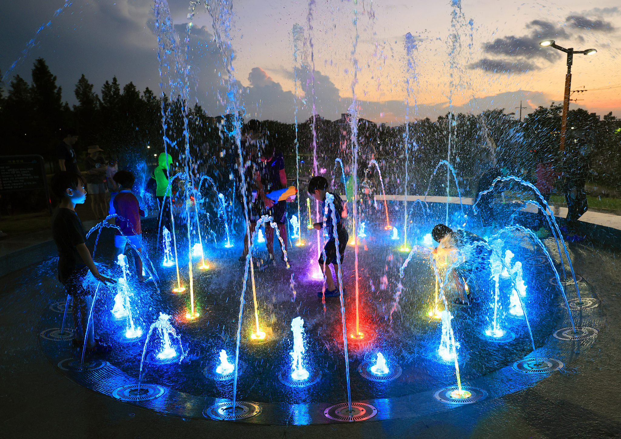 Children play and cool off in a water fountain at night in Jeju City, South Korea, August 17, 2024. /CFP