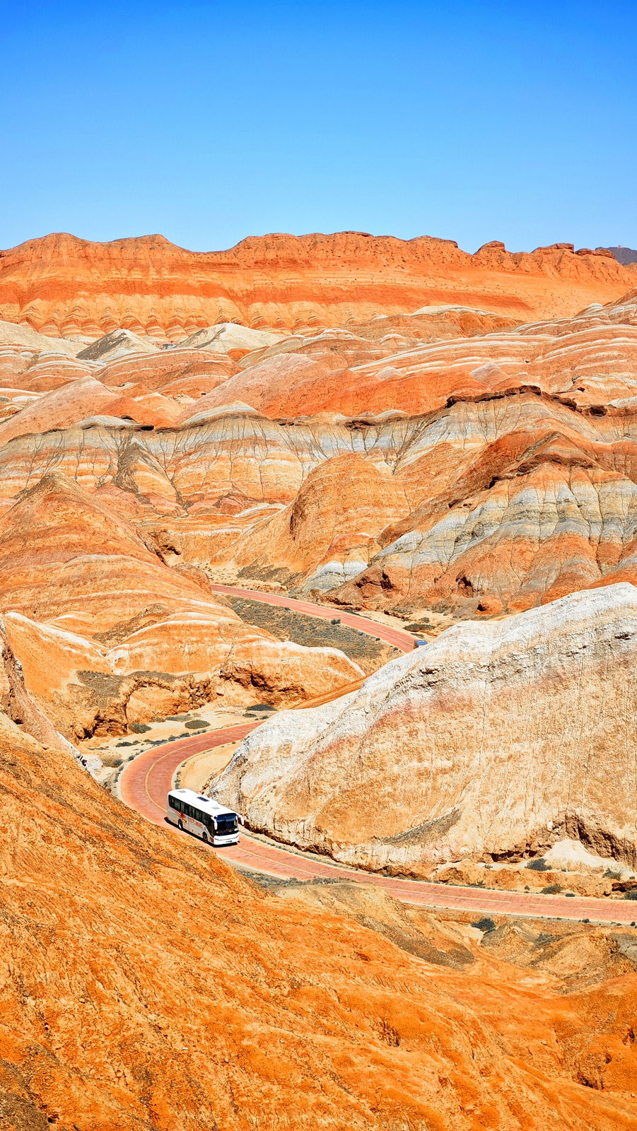 A bus traverses the vibrantly hued mountains at the Colorful Danxia Scenic Area of the Danxia National Geological Park in Zhangye, Gansu Province on August 18, 2024. /CFP