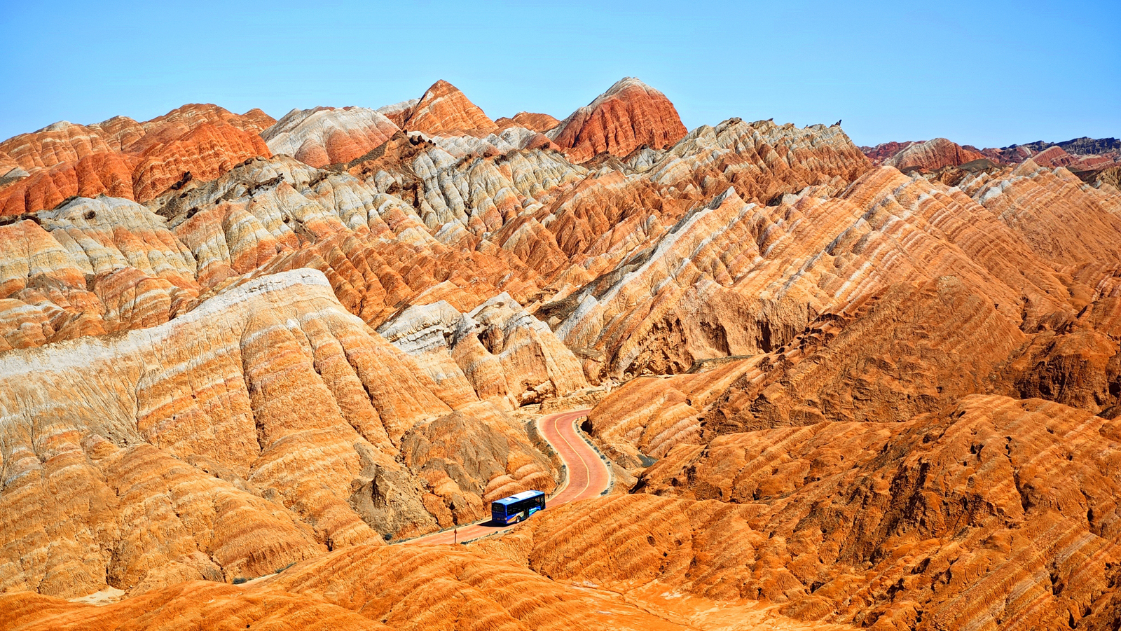 A bus traverses the vibrantly hued mountains at the Colorful Danxia Scenic Area of the Danxia National Geological Park in Zhangye, Gansu Province on August 18, 2024. /CFP