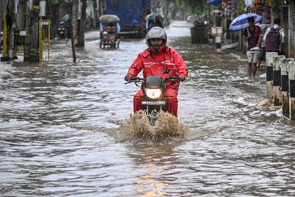 A man riding a motorbike moves through a flooded street after heavy rainfall during monsoon in Guwahati, the largest city of Assam State, India, August 20, 2024. /CFP