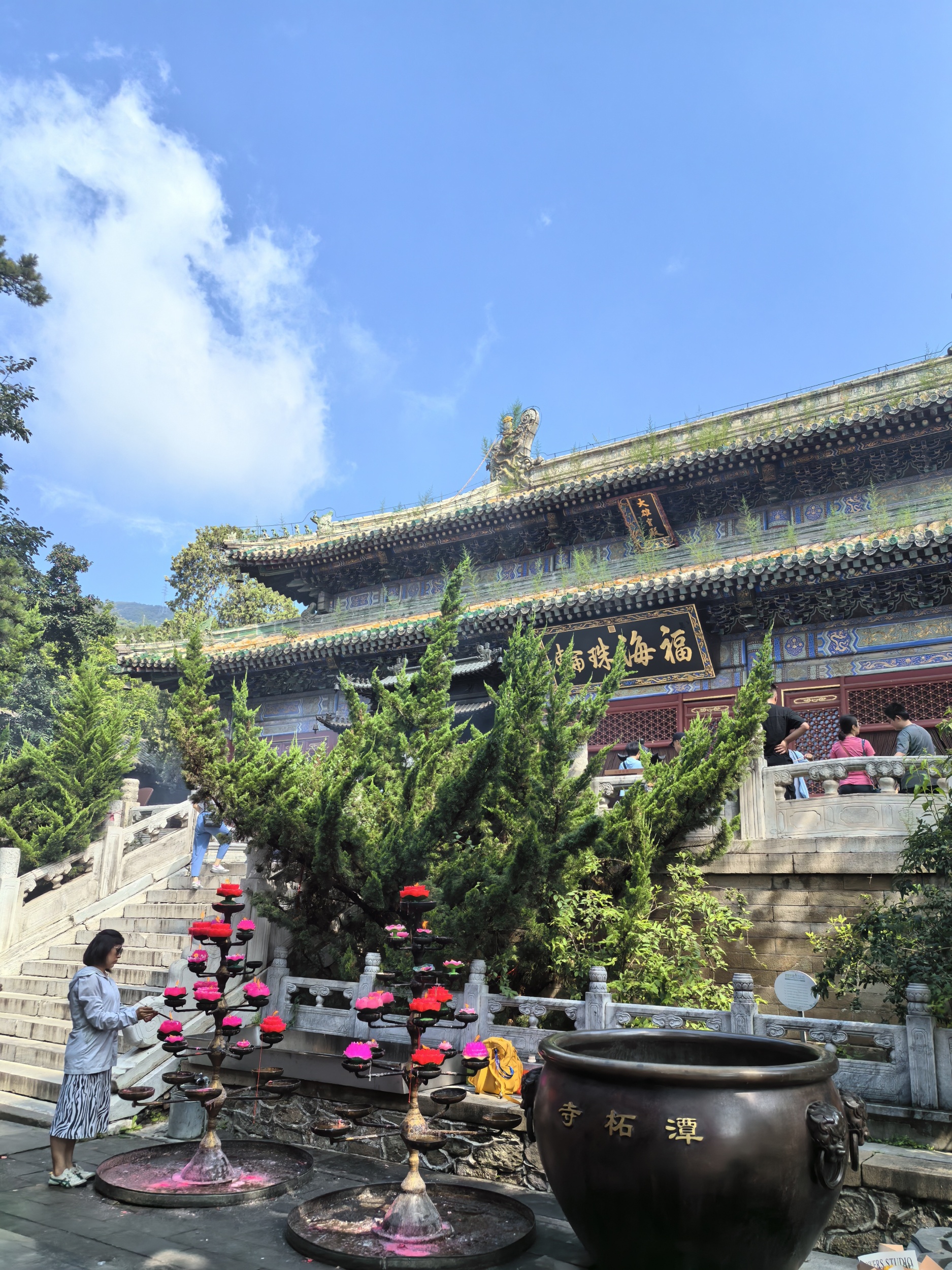 A woman burns incense for blessings at the Tanzhe Temple in Beijing on August 4, 2024. /CGTN