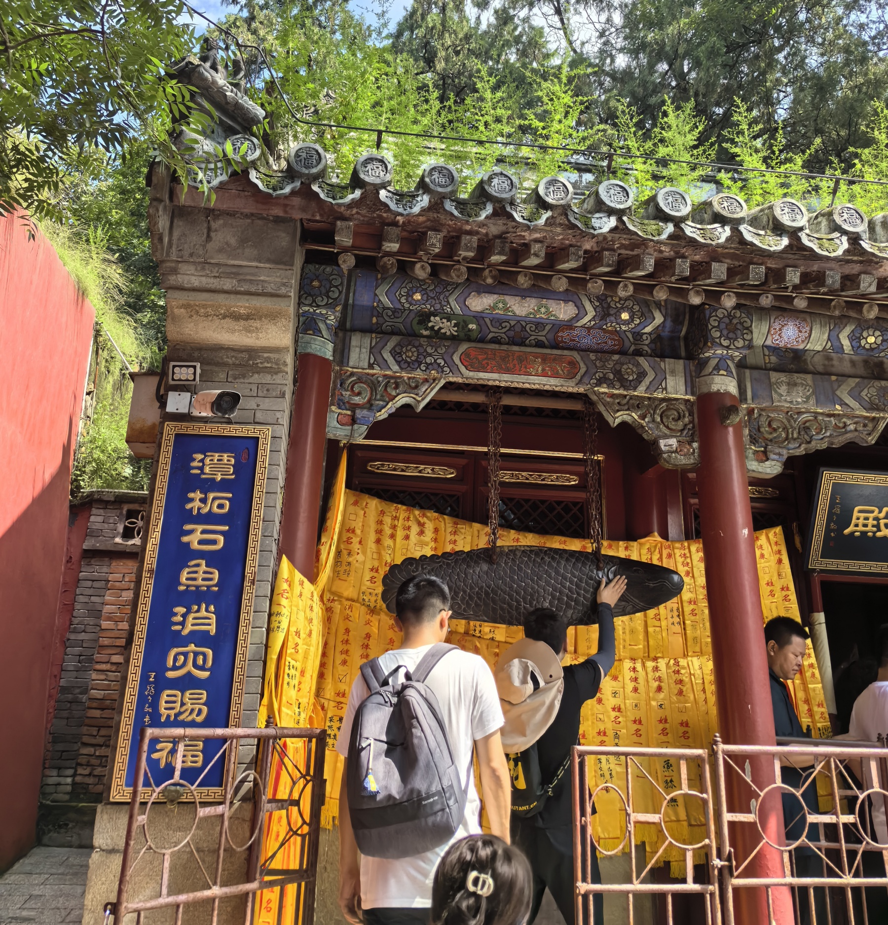 People queue in a line to touch a stone fish to pray for good health at the Tanzhe Temple in Beijing on August 4, 2024. /CGTN