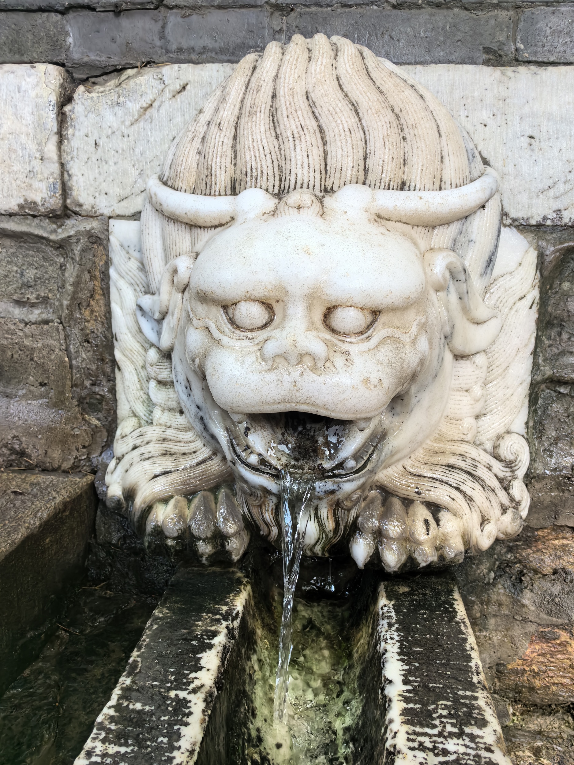 A stone lion with a water outlet in its mouth is seen at the Tanzhe Temple in Beijing on August 4, 2024. /CGTN