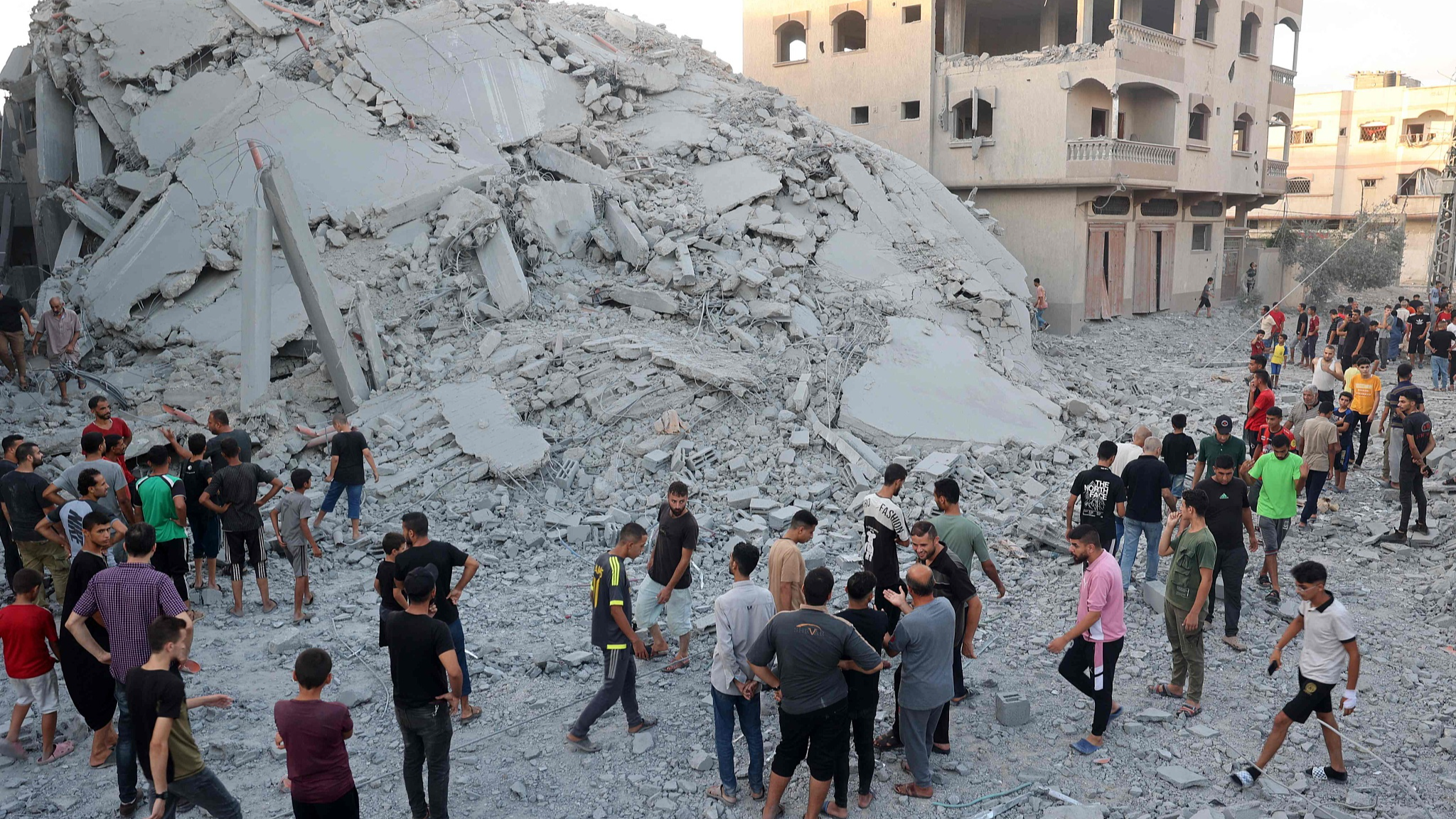 Palestinians gather to check a building shortly after it was leveled by Israeli bombing in the Nuseirat refugee camp in the central Gaza Strip,  August 22, 2024. /CFP