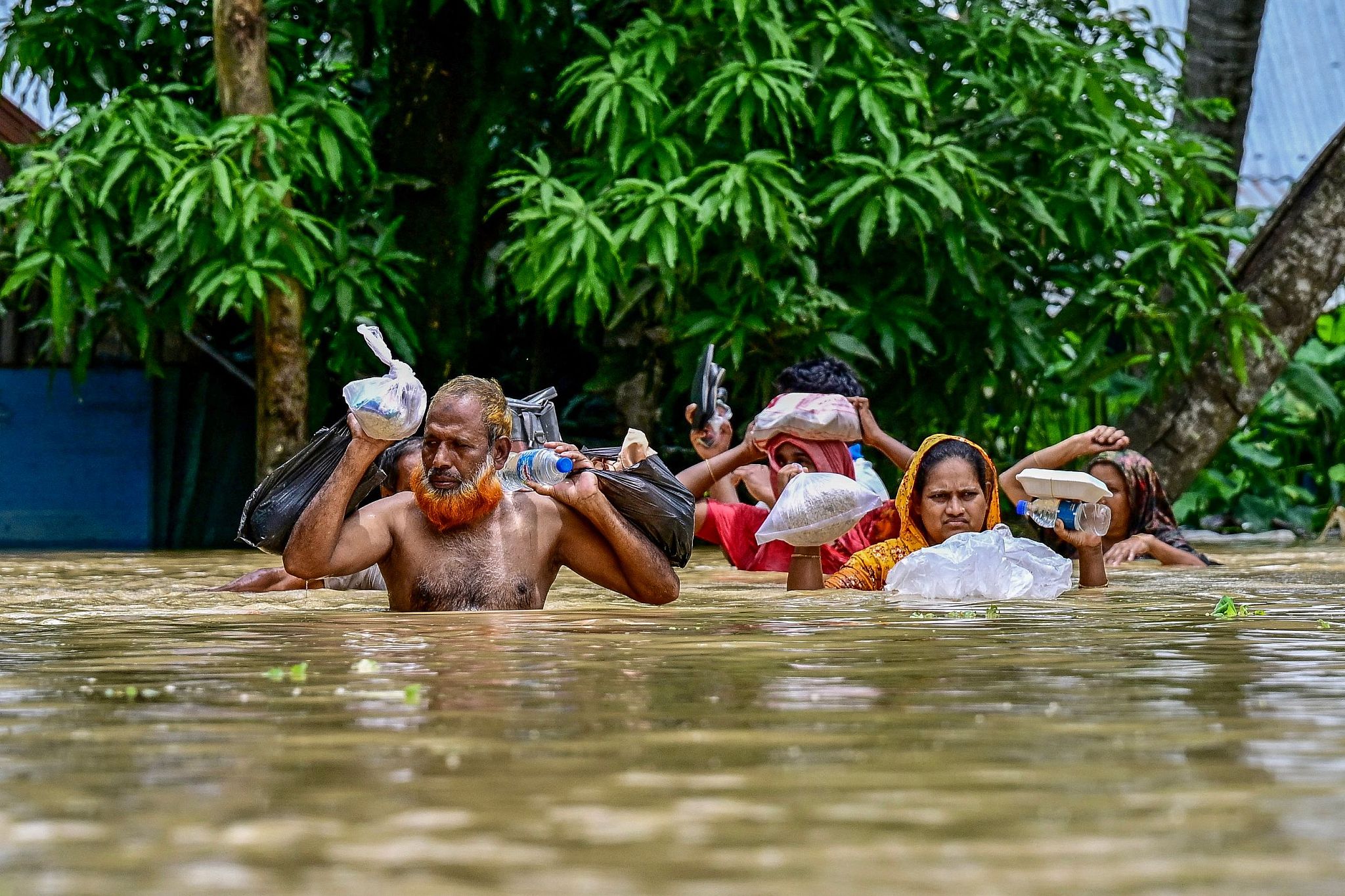 People carrying relief materials wade through flood waters in Feni, in southeastern Bangladesh, August 24, 2024. /CFP