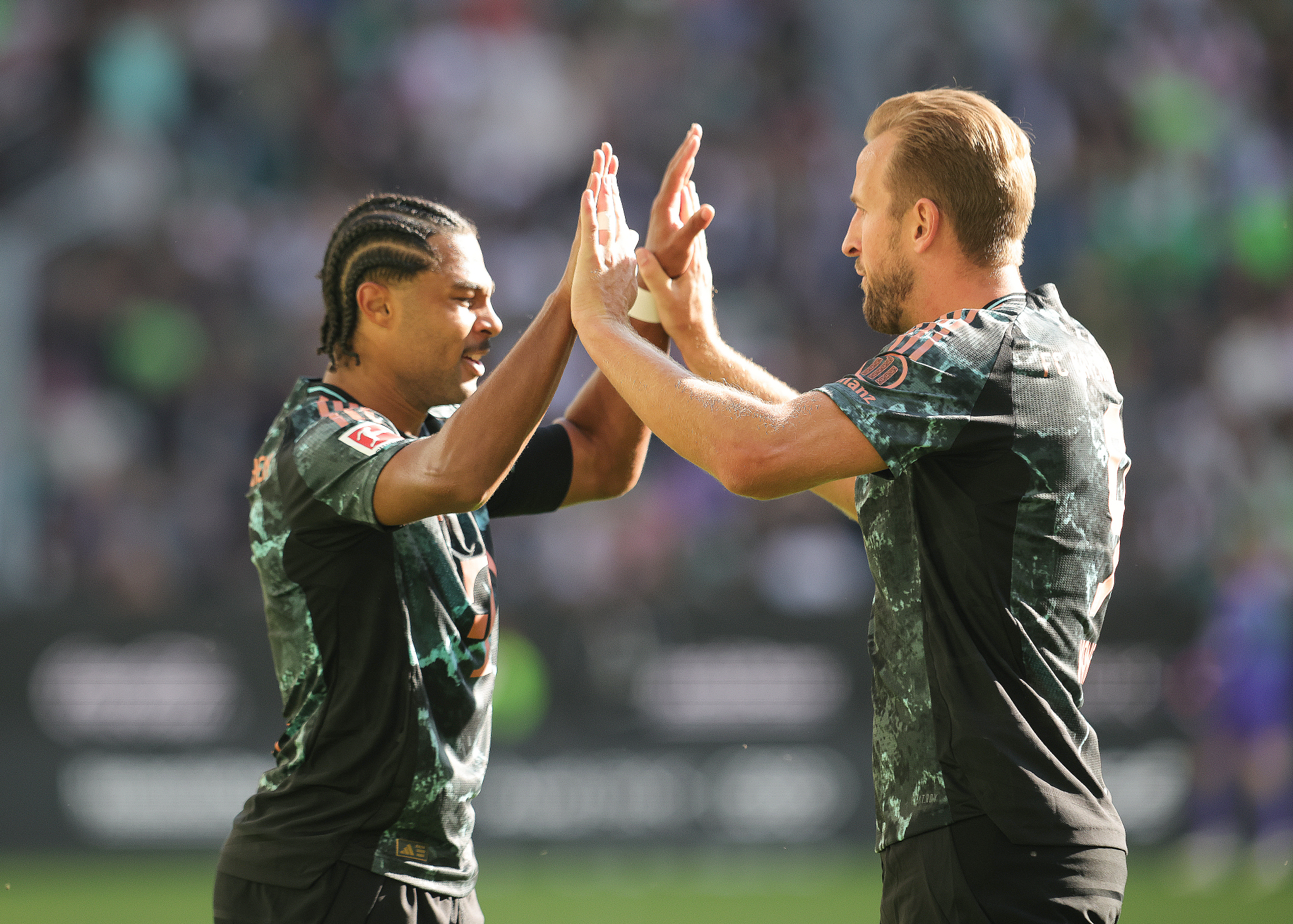 Bayern Munich's Serge Gnabry (L) and Harry Kane celebrate their team's third goal against Wolfsburg in a German Bundesliga match at the Volkswagen Arena in Wolfsburg, Germany, August 25, 2024. /CFP