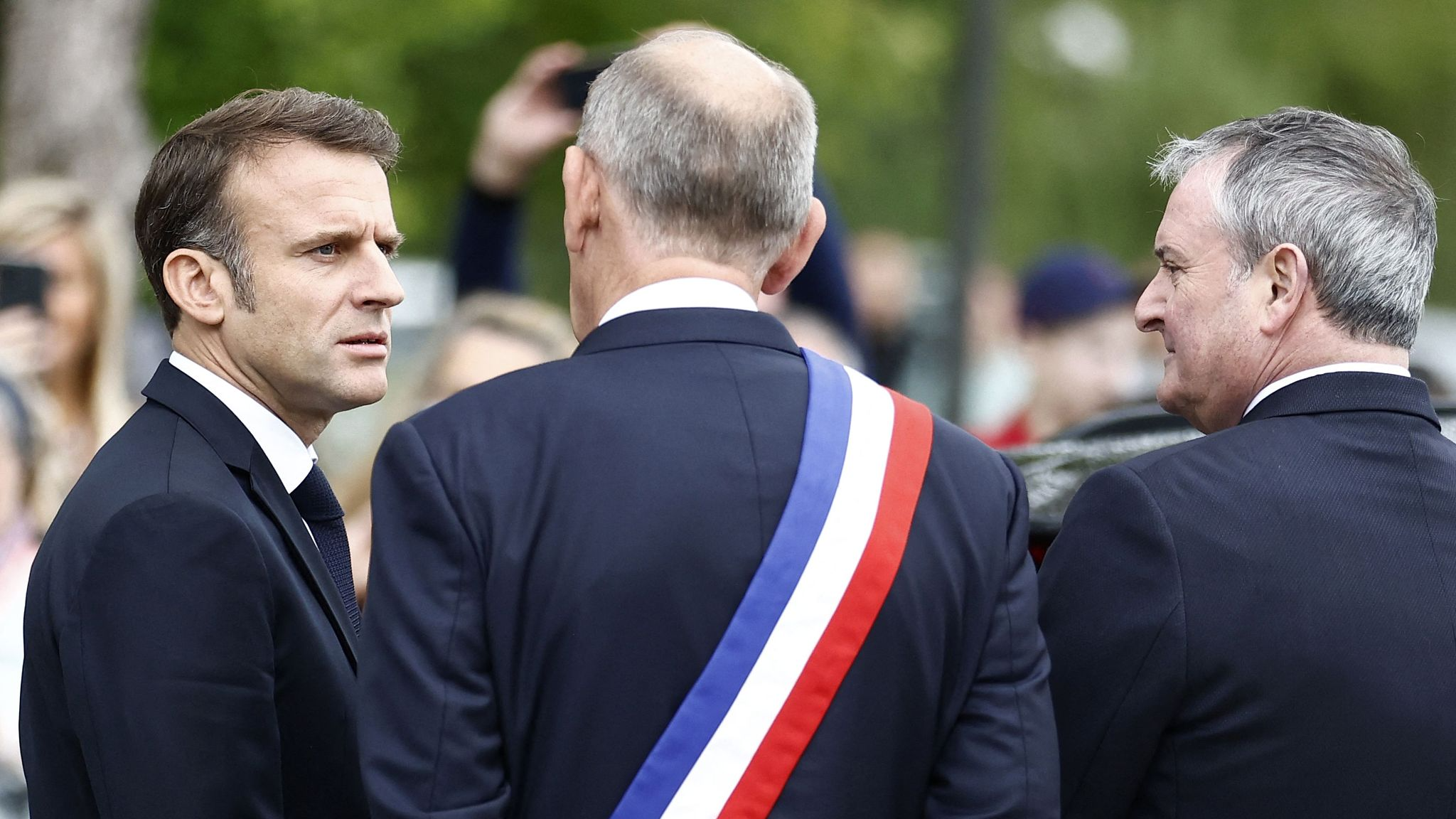 French President Emmanuel Macron, L, talks with the mayor of Le Touquet Daniel Fasquelle as he arrives to vote in the second round of France's legislative election at a polling station in Le Touquet, northern France, July 7, 2024. /CFP