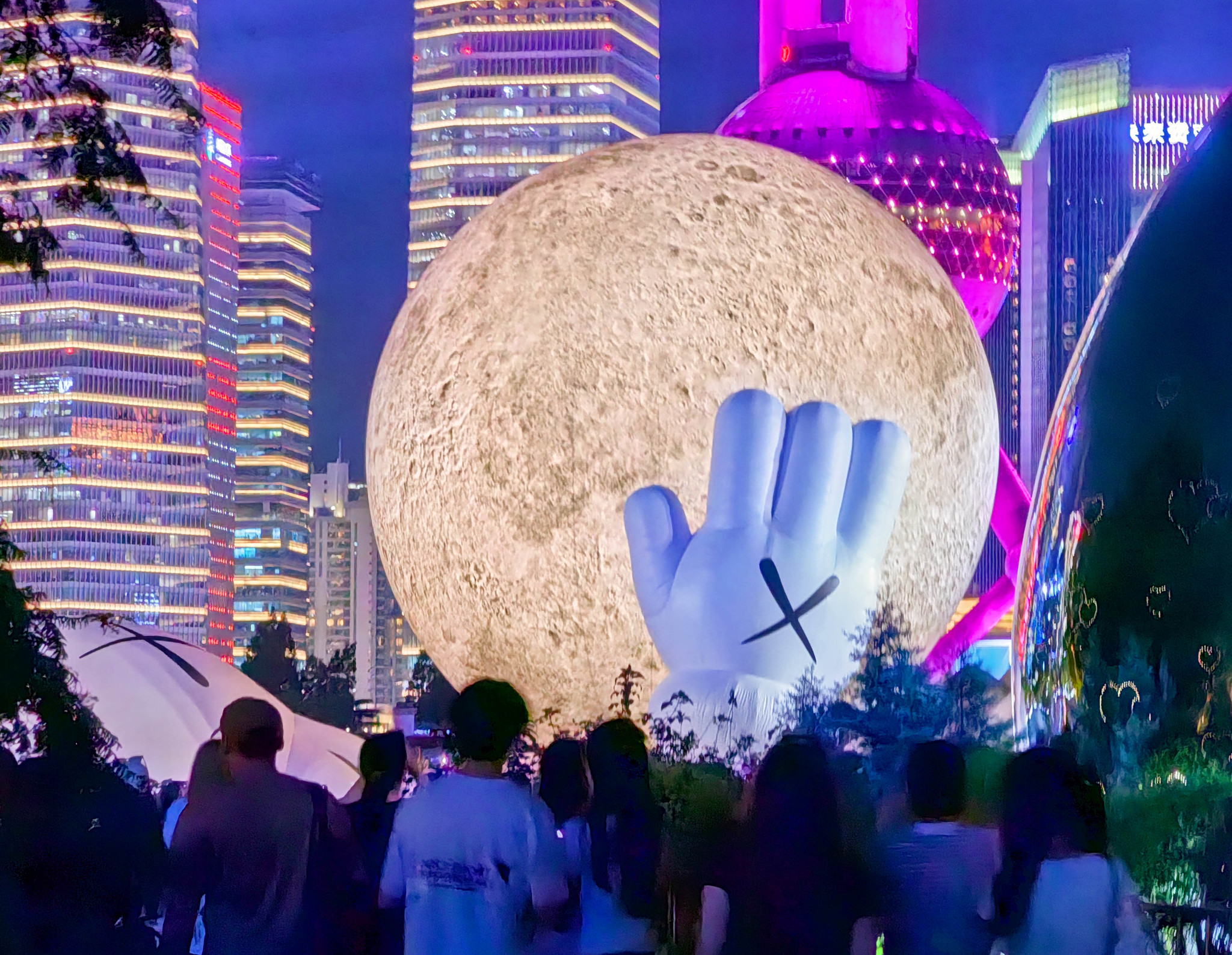 A giant inflatable sculpture by KAWS, featuring this American artist's iconic Companion figure cradling a glowing moon and gazing toward the sky, draws crowds to the North Bund in Shanghai on August 29, 2024. /CFP