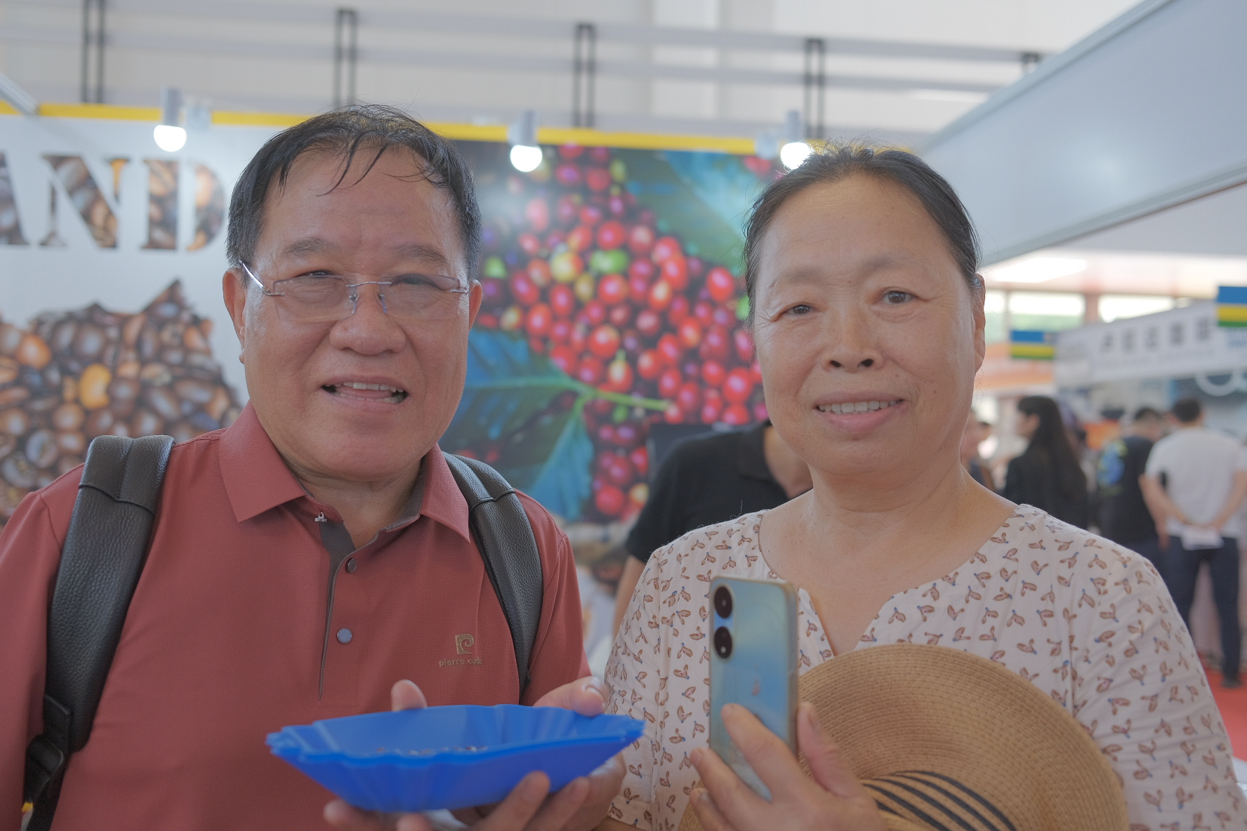 Yuan (R) and her husband show Uganda coffee beans at the 2024 Cafe Show China, August 30, 2024. /CGTN