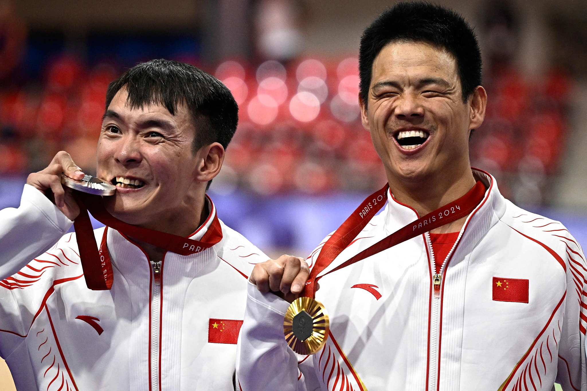 Gold medalist Li Zhangyu (R) and silver medalist Liang Weicong celebrate on the podium of the men's C1 3,000m cycling individual pursuit track event during the Paris 2024 Paralympic Games, August 29, 2024. /CFP