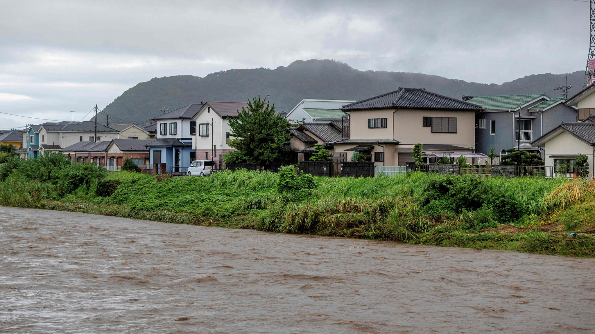 Muddy waters of the Kaneme River flow past houses lined up behind the river's bank in the aftermath of Typhoon Shanshan in Hiratsuka City, Kanagawa prefecture, Japan, August 30, 2024. /CFP