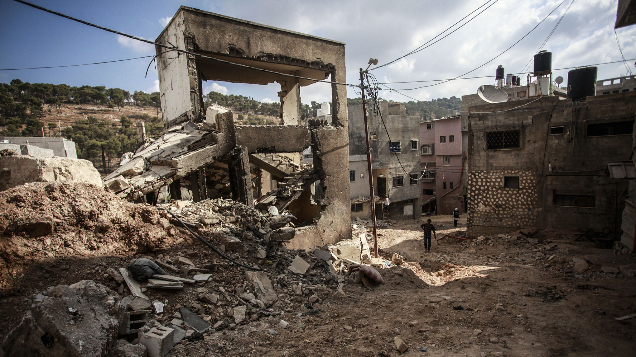 People walk past the devastation in the Nur Shams refugee camp near Tulkarem in the occupied West Bank in the aftermath of a large-scale Israeli military operation, August 30, 2024. /CFP