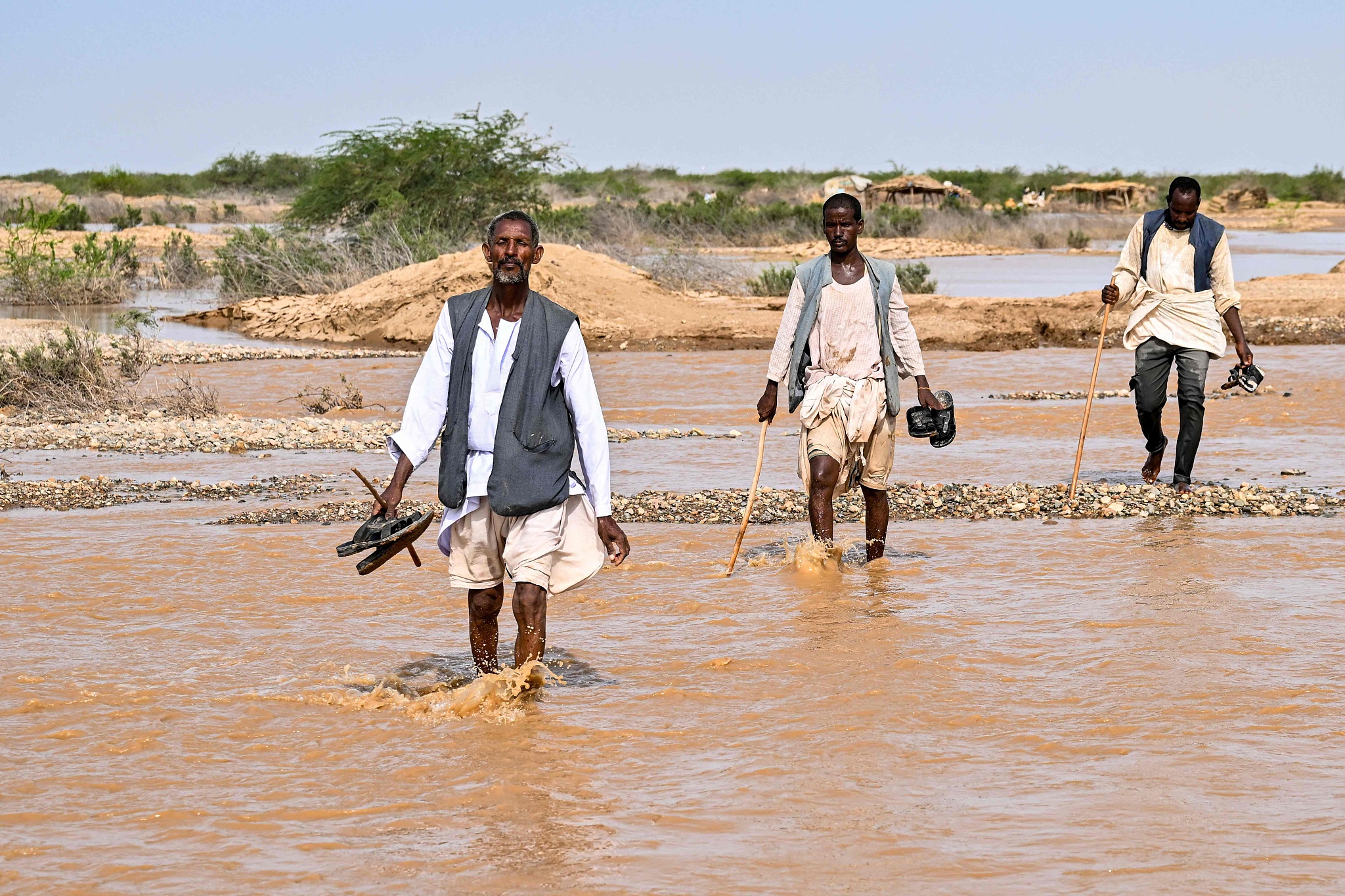 Men walk through an inundated area following recent heavy flooding in eastern Sudan, August 30, 2024. /CFP