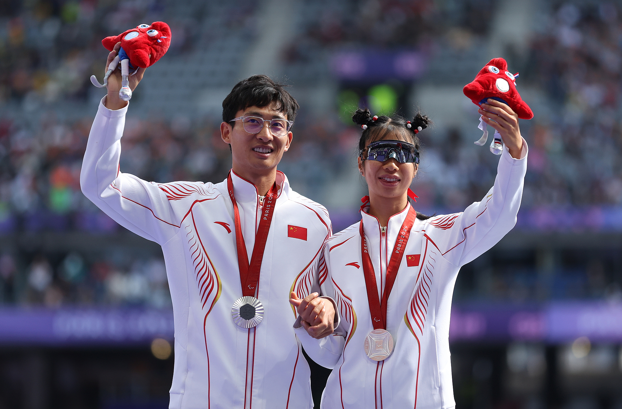 Silver medalist He Shanshan He (R) and her guide You Junjie pose for a photo during the women's 1500m T11 medal ceremony at the Paris Paralympic Games in Paris, France, September 2, 2024. /CFP