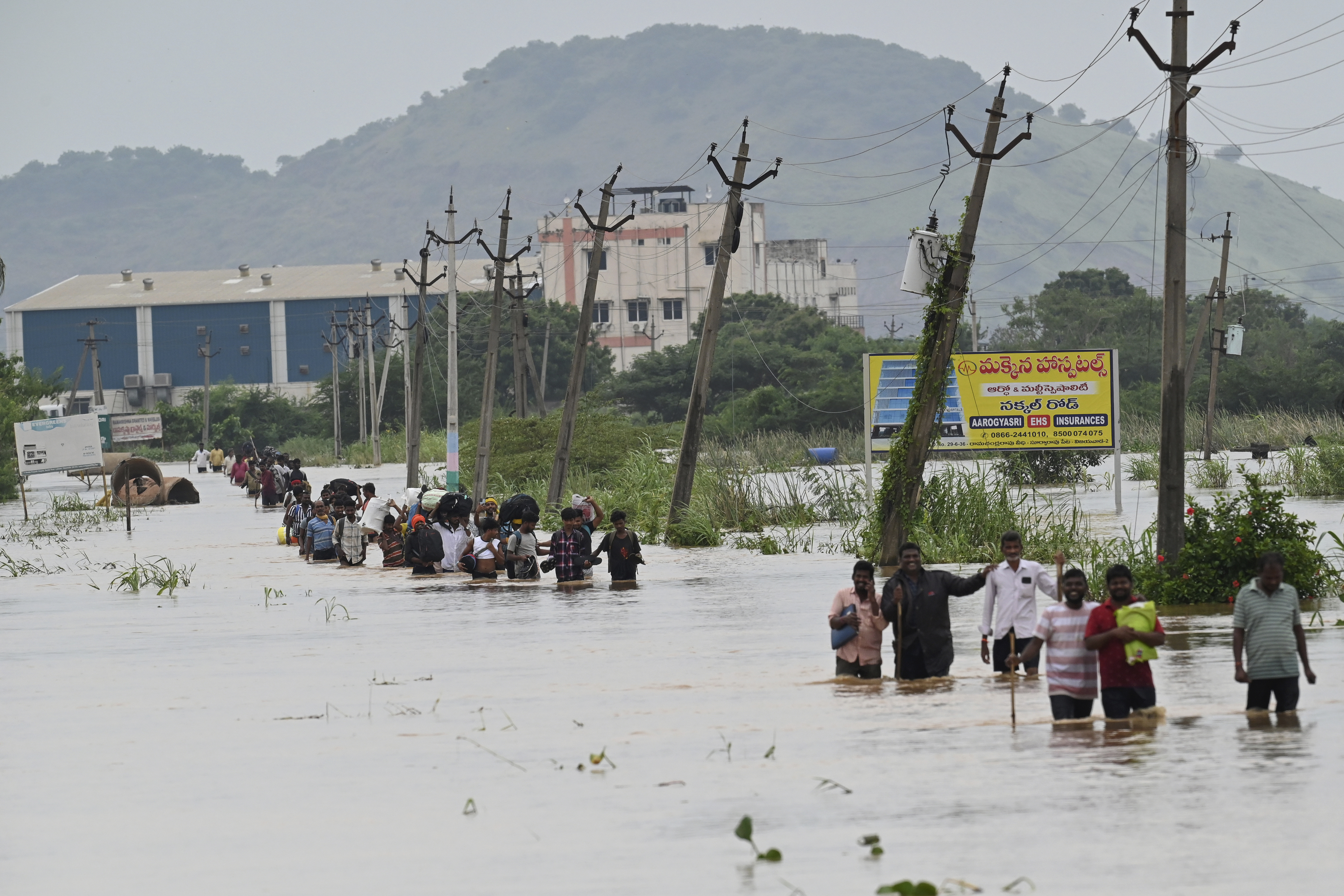 People, many carrying their belongings, wade through a flooded road after heavy rains in Vijayawada, India, Monday, Sept. 2, 2024. /AP Photo