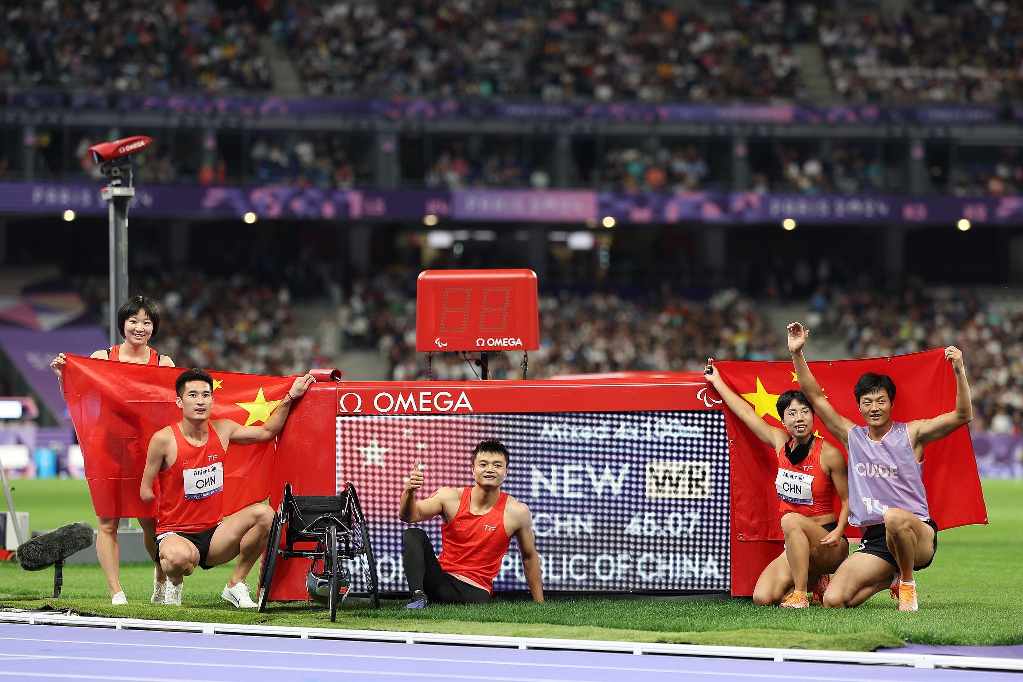 L-R: Gold medalists Wen Xiaoyan, Wang Hao, Hu Yang, Zhou Guohua and her guide Jia Dengpu of Team China pose next to a screen displaying their new world record of 45.07 after the para athletics 4x100m universal relay final during the Paris 2024 Paralympic Games in Paris, France, September 6, 2024. /CFP