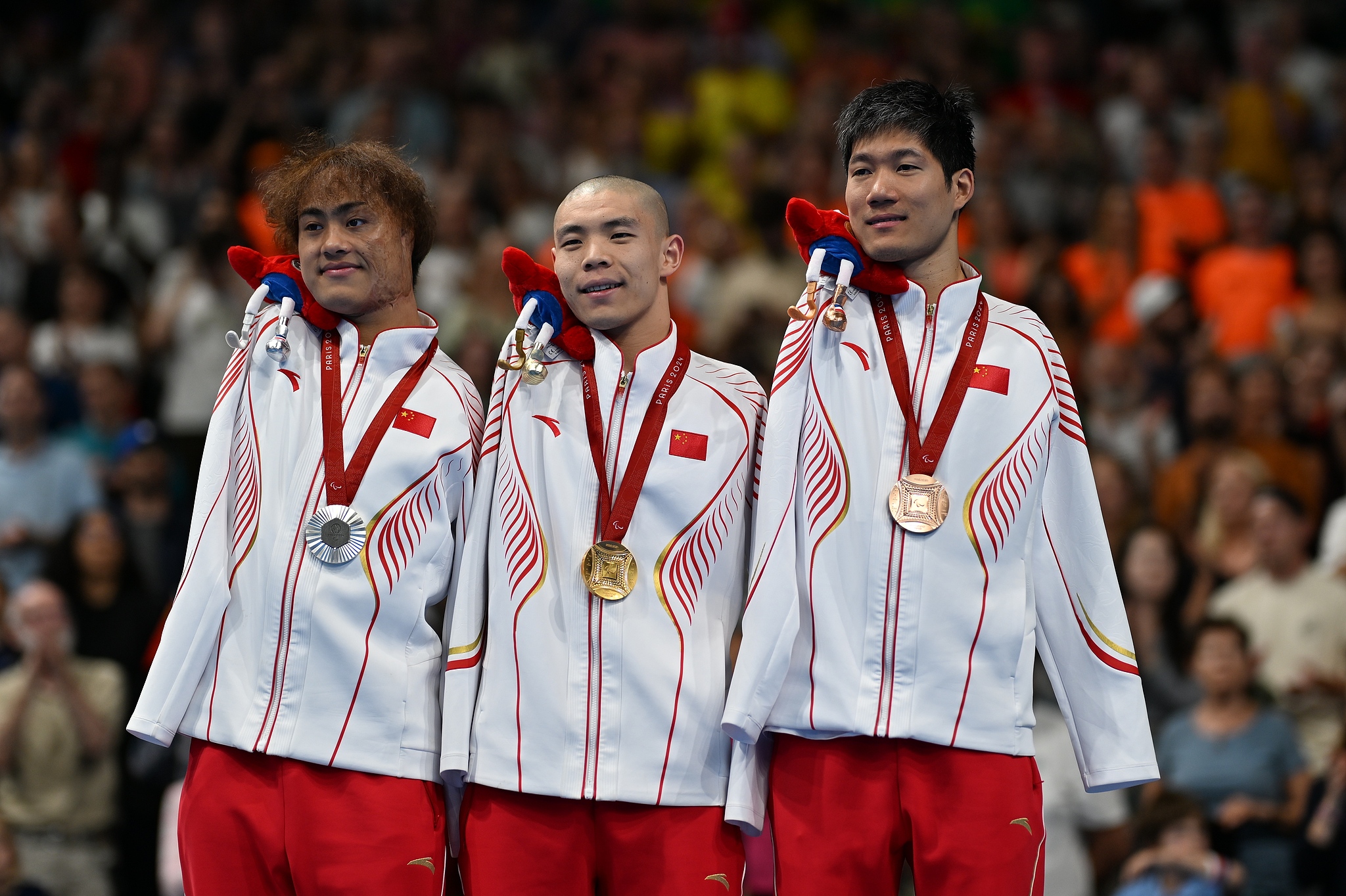 Gold medalist Guo Jincheng (C), silver medalist Yuan Weiyi (L), and bronze medalist Wang Lichao, all from Team China, stand at the podium after the para swimming men's 50m butterfly S5 final during the Paris 2024 Paralympic Games in Nanterre, France, September 6, 2024. /CFP 