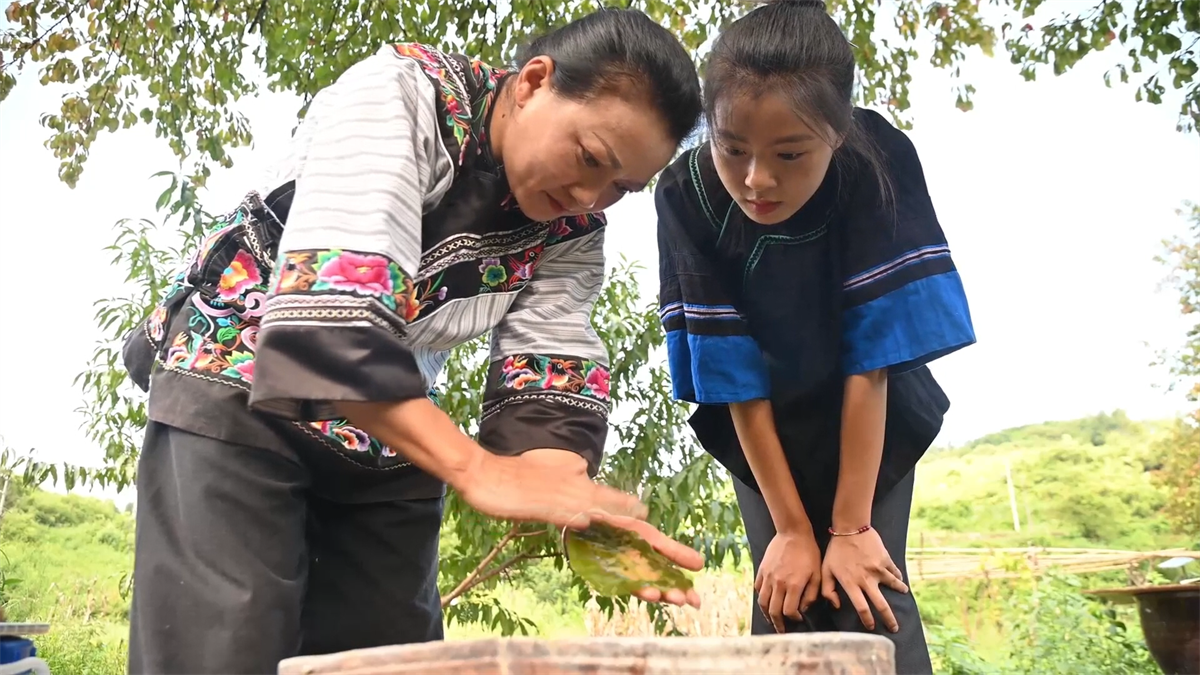 Yang Li teaches her apprentice how to extract veins from a leaf at a workshop in Tongren City, Guizhou Province. /Photo provided to CGTN