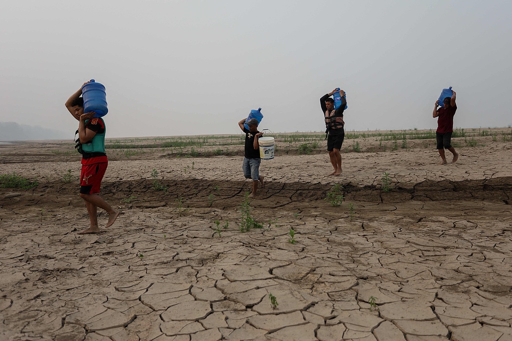 People carry drinking water along a sandbank of Madeira River in Amazonas state, northern Brazil, September 7, 2024. /CFP