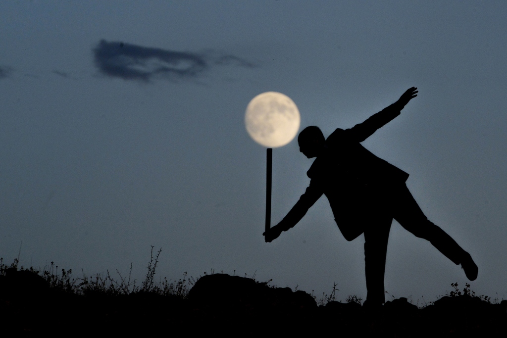 The shadow of a man holding a stick is seen in front of a supermoon in Turkey's Van. /CFP 