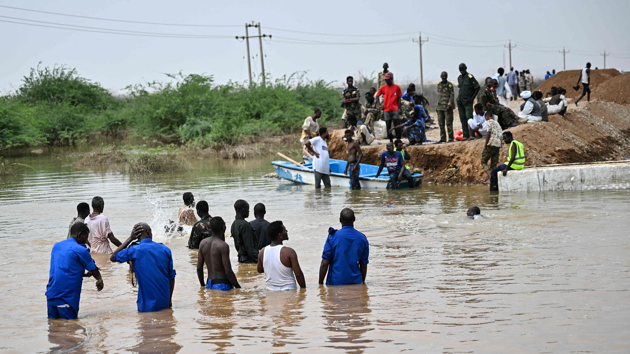 Sudanese army soldiers look on as people use a boat in an inundated area in Tokar in the Red Sea State, following recent heavy flooding in eastern Sudan, September 5, 2024. /CFP