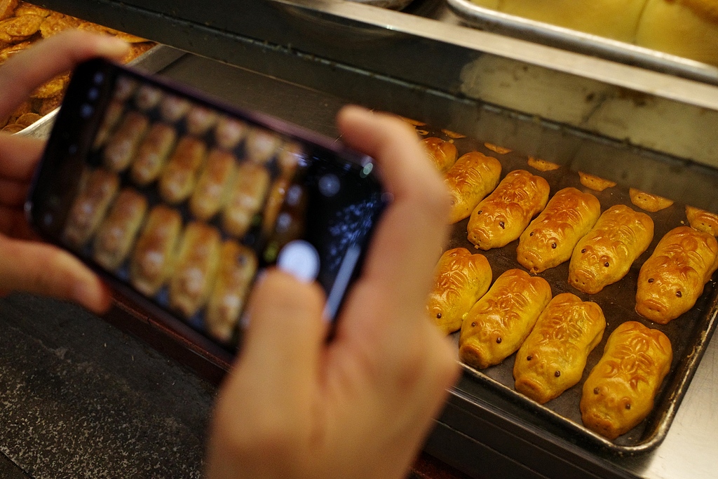 Golden pig mooncakes attract visitors to take photos at a bakery in Guangzhou, Guangdong Province on September 10, 2024. Pigs symbolize wealth and fertility in Chinese culture. /CFP