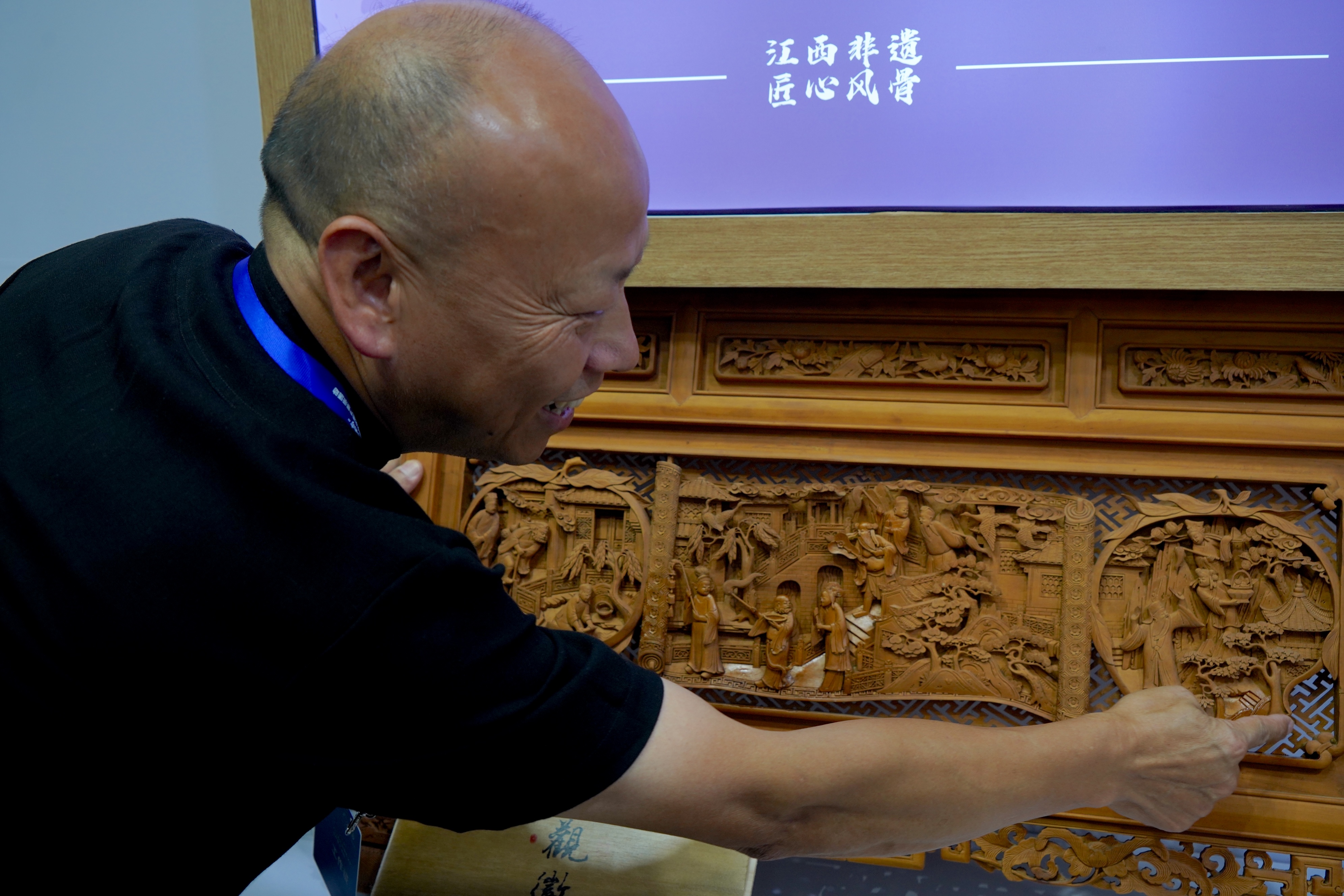 An artisan explains details of Wuyuan wood carving at an intangible cultural heritage exhibition held this autumn in northwest China's Xinjiang Uygur Autonomous Region. /CGTN