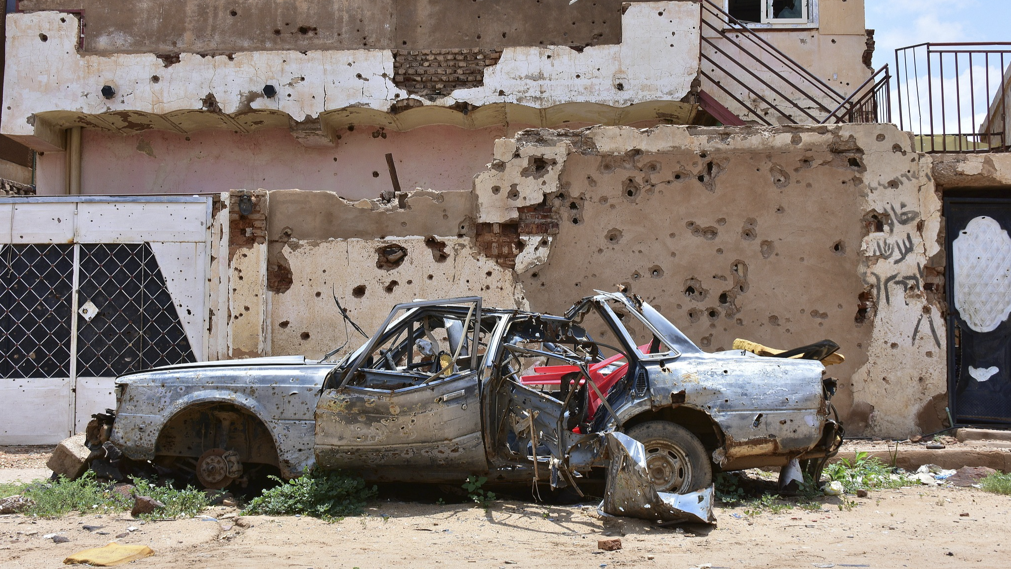 A destroyed car stands in front of a house full of bullet holes in Omdurman, Sudan, August 27, 2024. /CFP