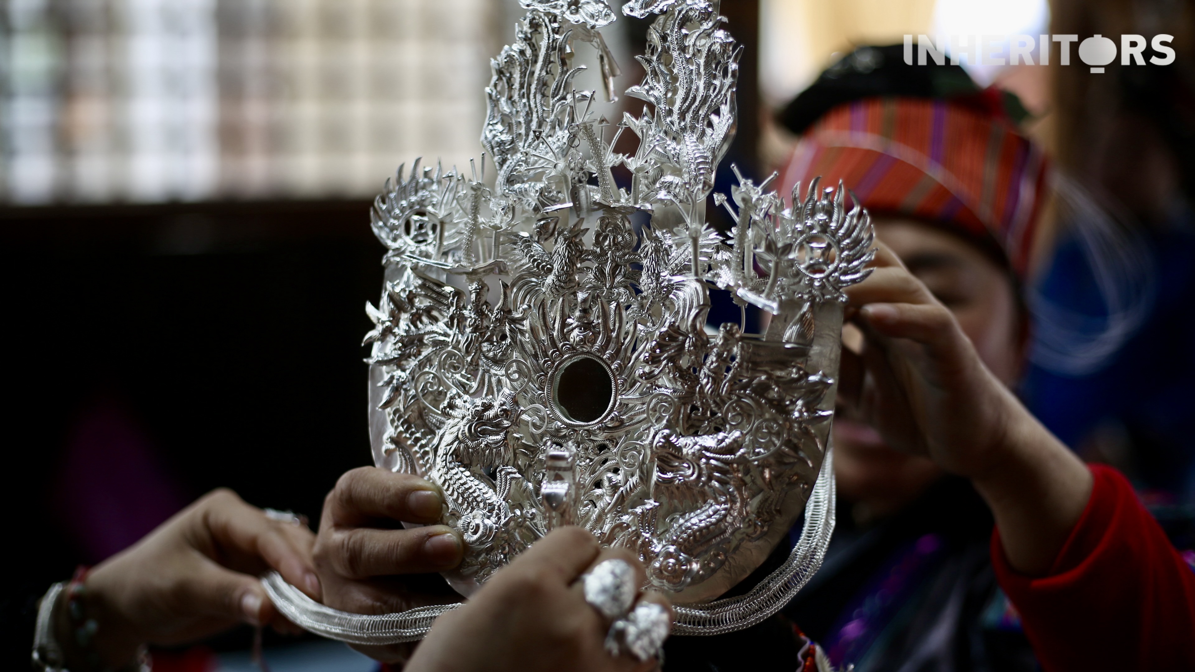 A Miao woman helps her sister to put on some silver. /CGTN