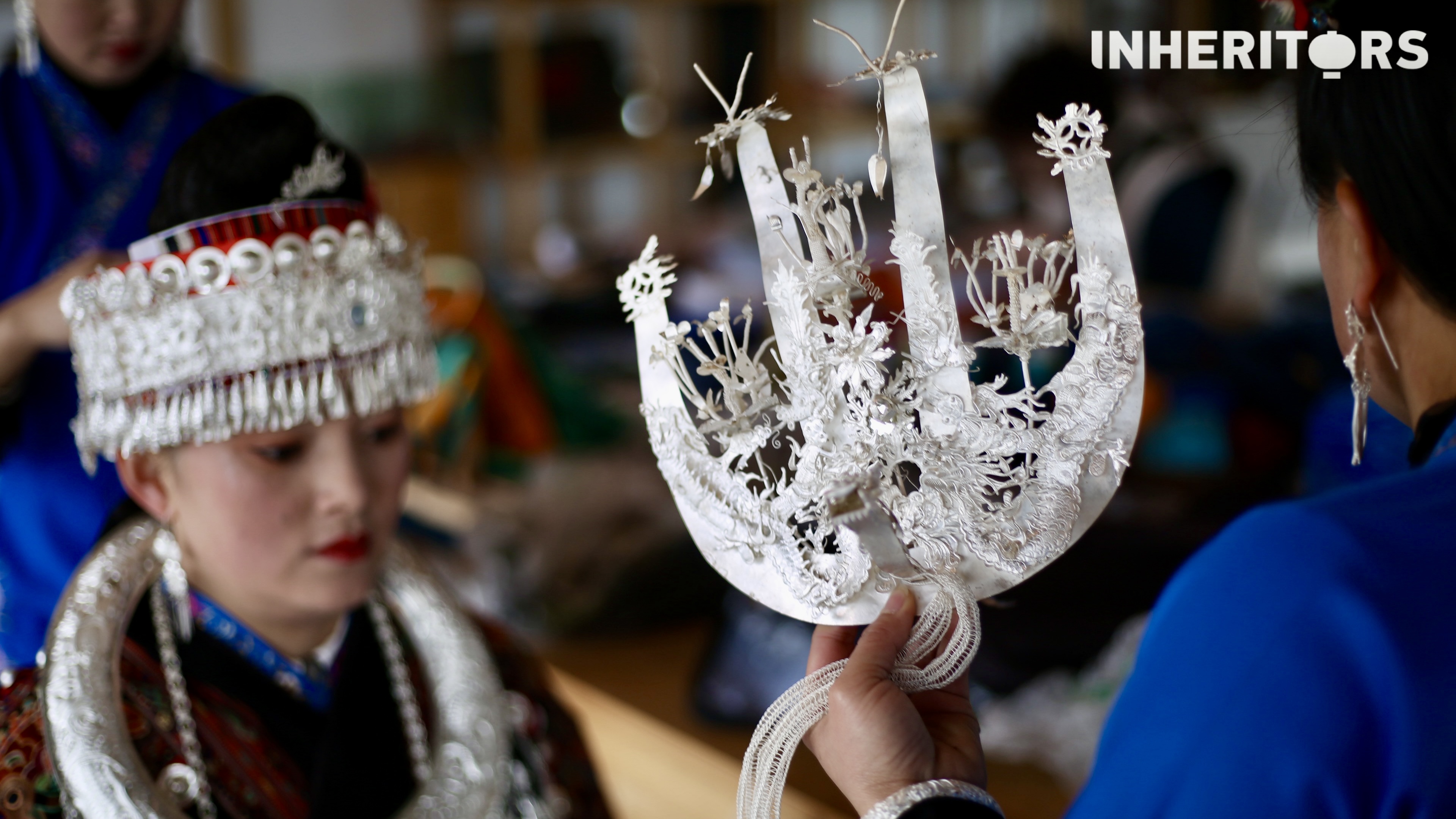 A Miao woman helps her sister to put on some silver. /CGTN