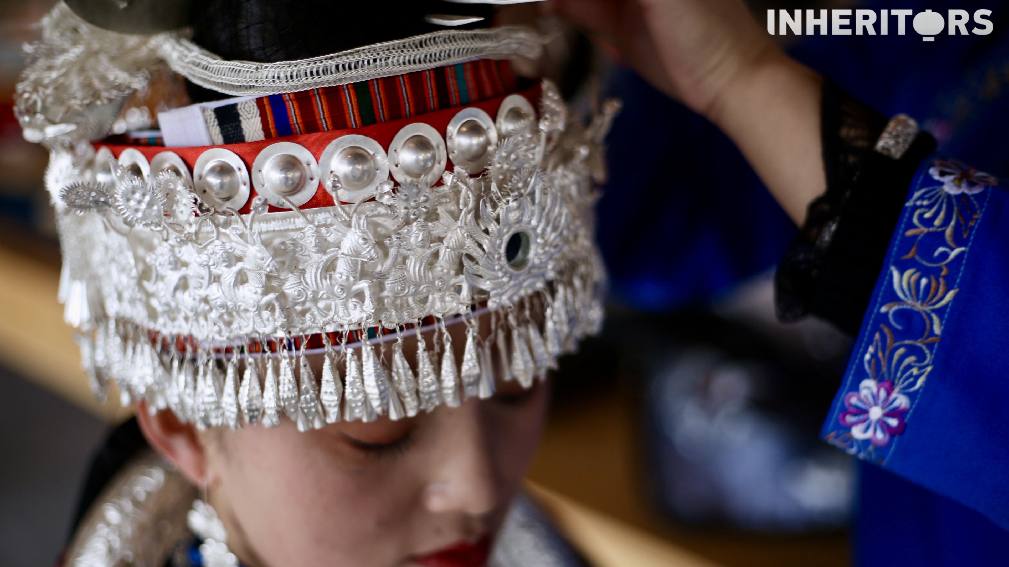 A Miao woman helps her sister to put on some silver. /CGTN