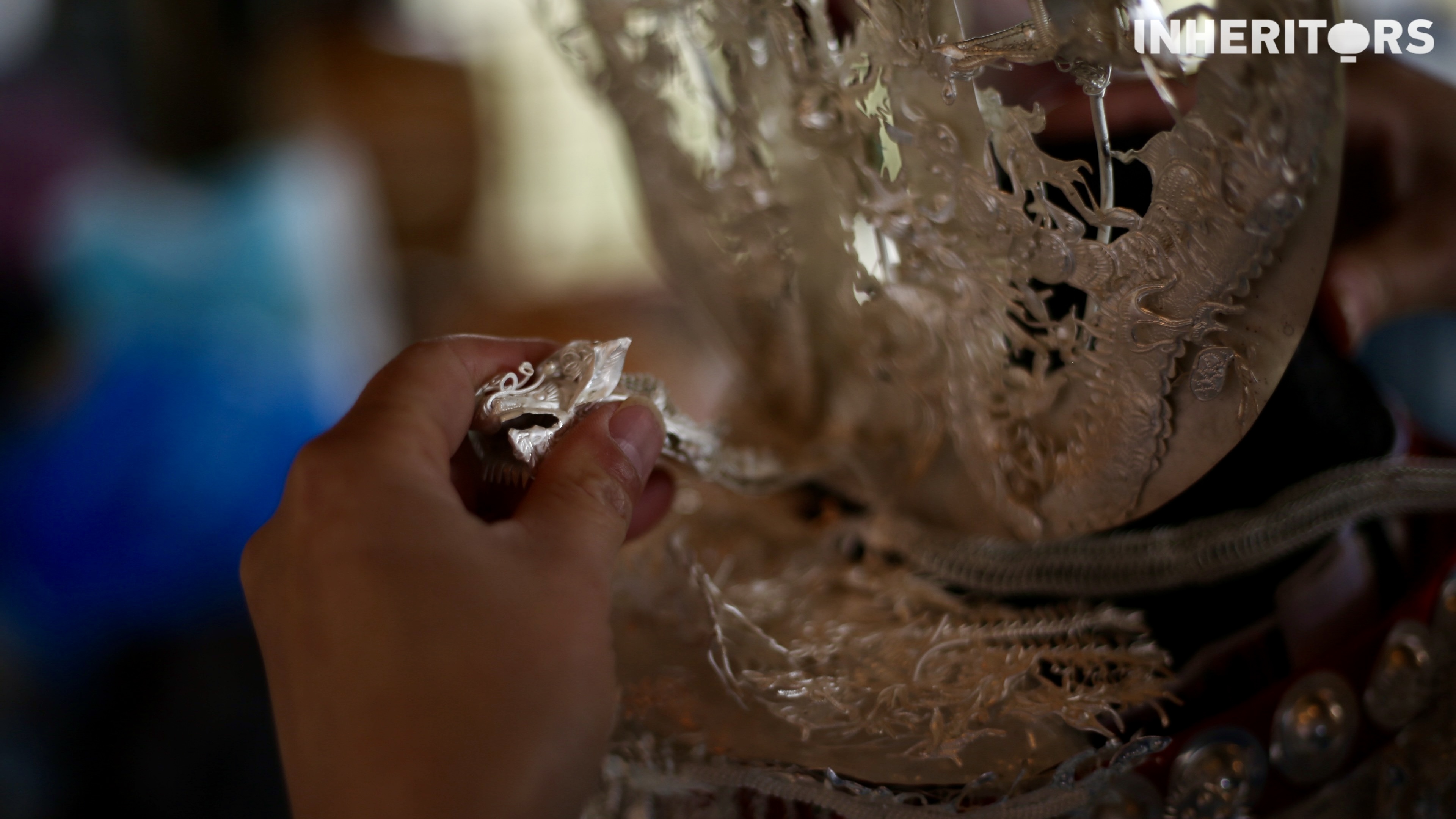 A Miao woman helps her sister to put on some silver. /CGTN