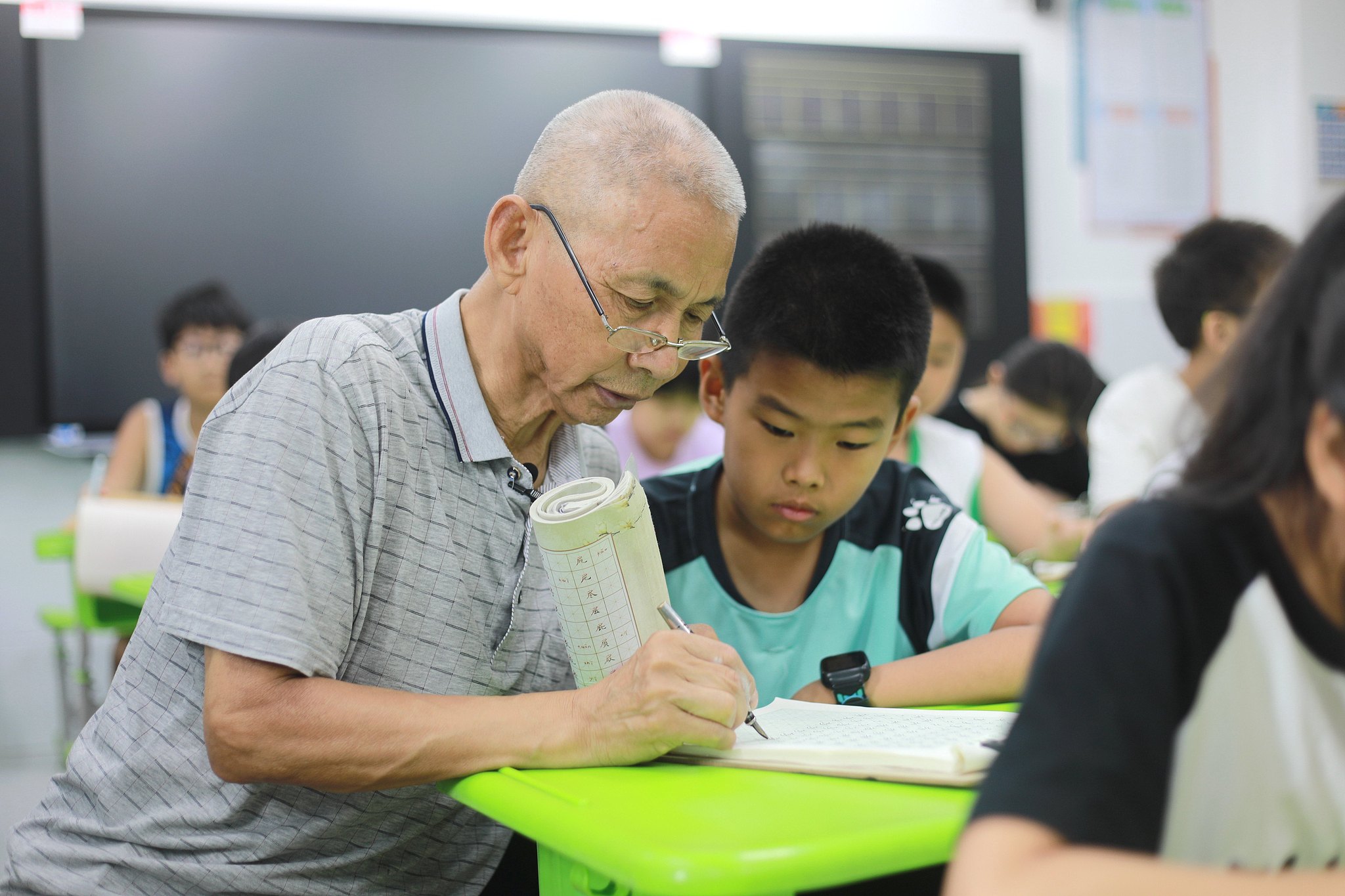 A retired man teaches hard pen calligraphy to students at a primary school in Handan City, Hebei Province, northern China, July 10, 2024. /CFP