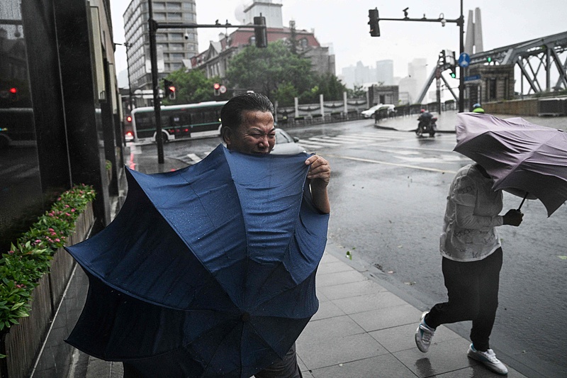 Pedestrians struggle with their umbrellas in strong winds and rain from the passage of Typhoon Bebinca in Shanghai, September 16, 2024. /CFP