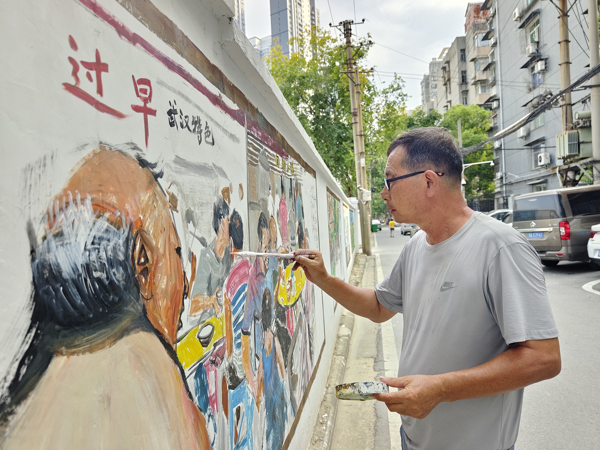 A retired art teacher paints a mural on a wall on a street in Hanyang District of Wuhan, central China's Hubei Province, August 18, 2024. /CFP
