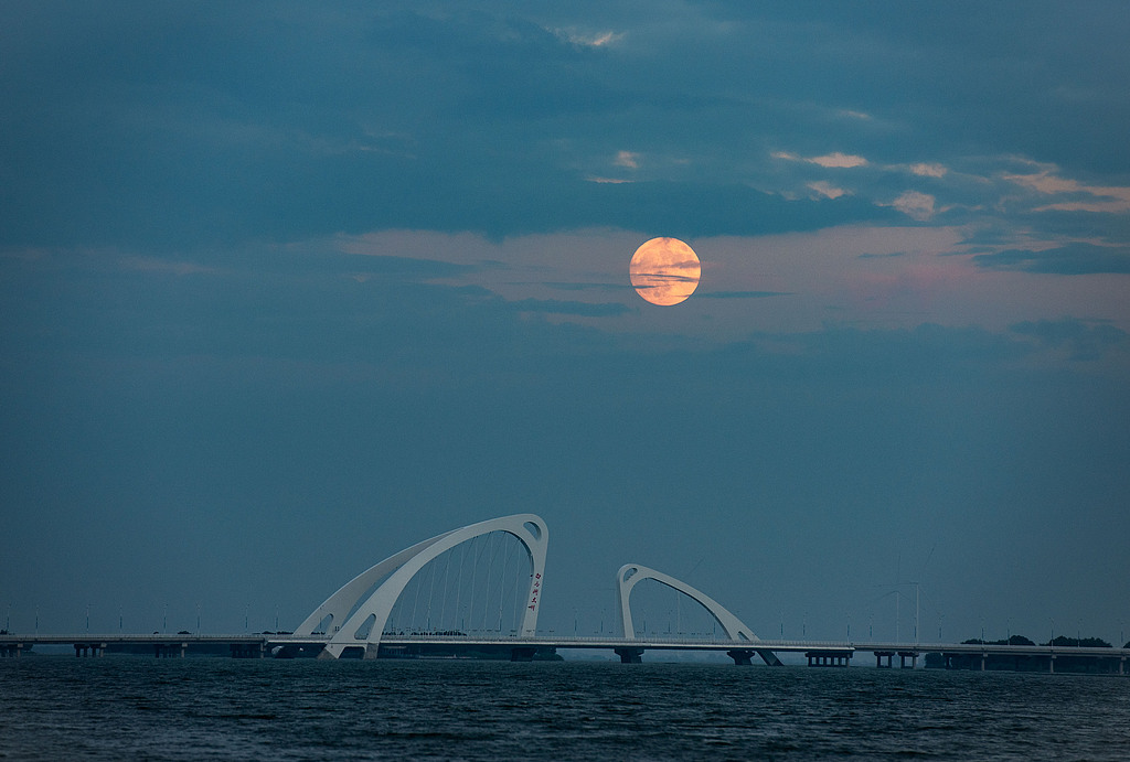 The moon rises up from a lake in Huaian City in east China's Jiangsu Province, September 17, 2024. /CFP