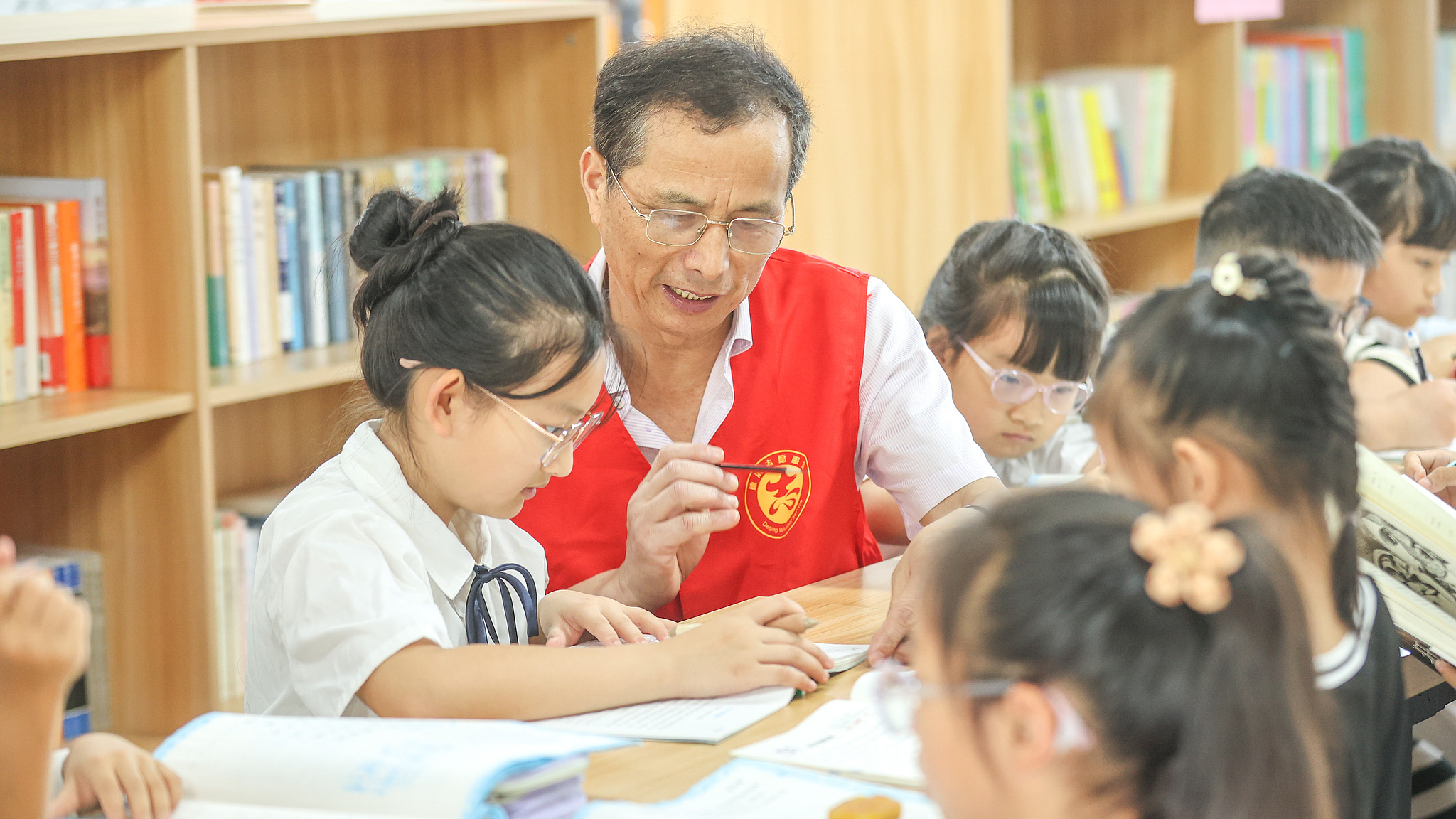 Seorang guru pensiunan menjadi relawan untuk membantu anak-anak membaca di Huzhou, Provinsi Zhejiang, Tiongkok timur, 3 Juli 2024. /CFP 