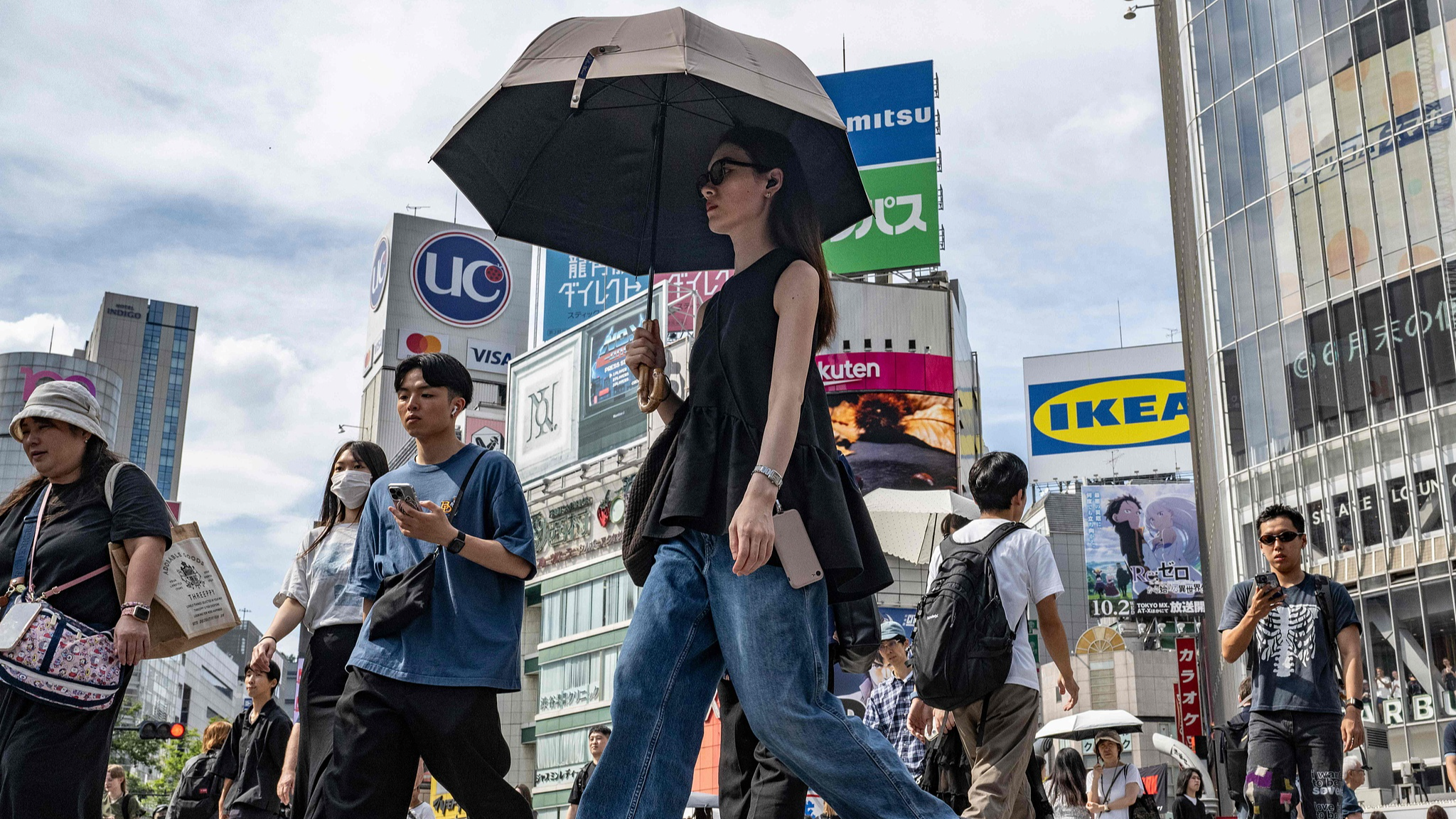 A woman uses a parasol to shelter from the sun while crossing a street in Tokyo, September 19, 2024. /CFP