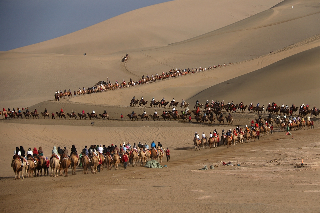 Visitors enjoy the fun of camel riding at the Mingsha Mountain and Crescent Spring scenic spot in Dunhuang, Gansu Province, September 17, 2024. /CFP