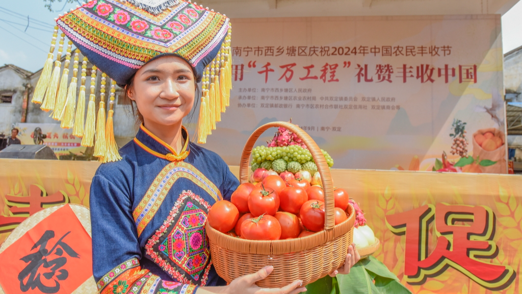 Seorang wanita berpakaian etnik Zhuang terlihat memegang sekeranjang tomat di Nanning, Guangxi pada 20 September 2024. /IC