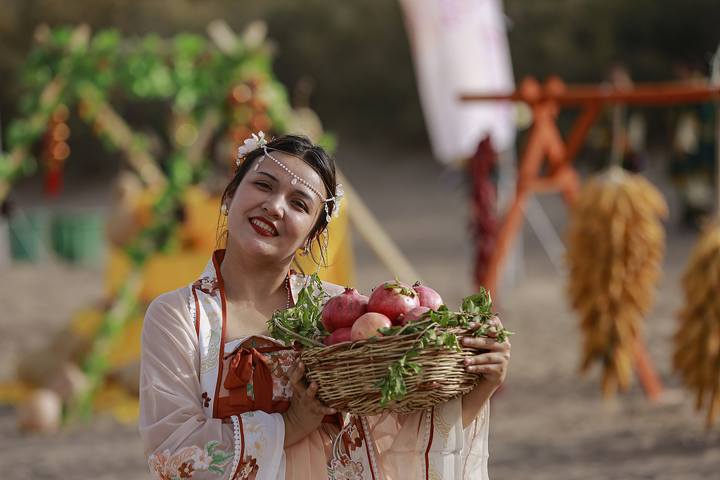 A farmer poses for a photo with freshly picked pomegranates on September 21, 2024, Aksu, Xinjiang Uygur Autonomous Region. /CFP