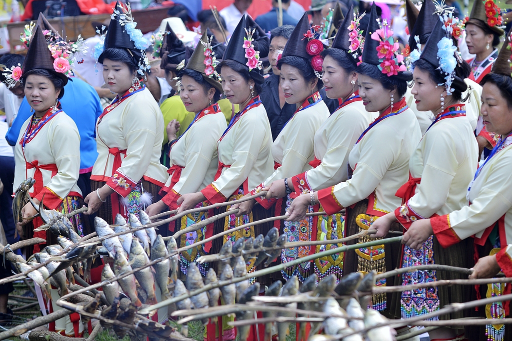 Miao women dressed in ethnic costumes from Gaowen Village, Guangxi Zhuang Autonomous Region, grill fish on September 20, 2024 to welcome the harvest season. /CFP