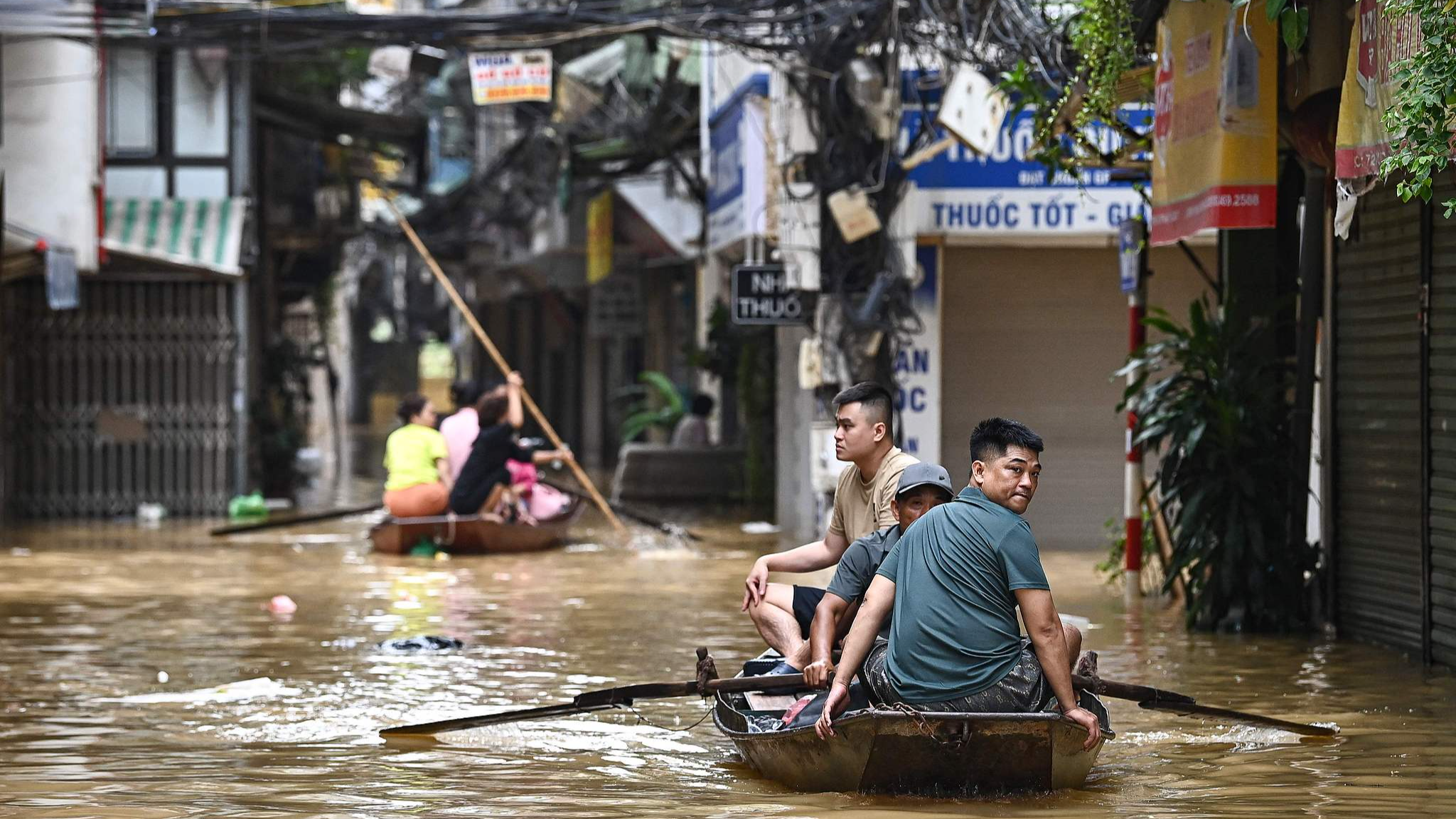 People wade through flood waters on a boat in Hanoi, Vietnam, September 12, 2024. /CFP