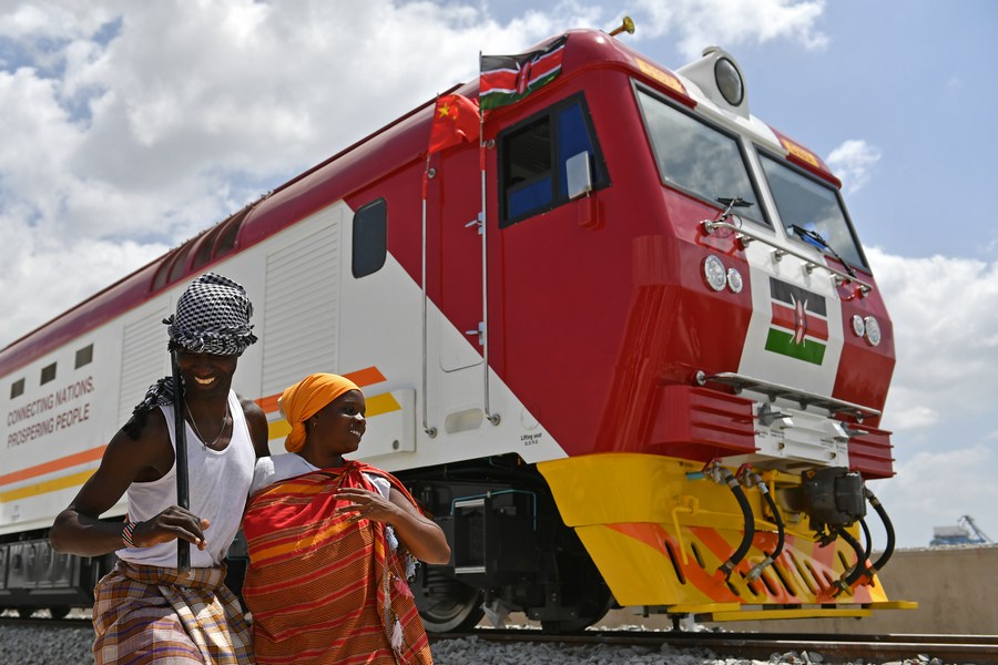 Kenyans celebrate next to one of the first batch of locomotives that were made by Chinese companies for the Mombasa-Nairobi Standard Gauge Railway, Mombasa, Kenya, on January 11, 2017. /Xinhua