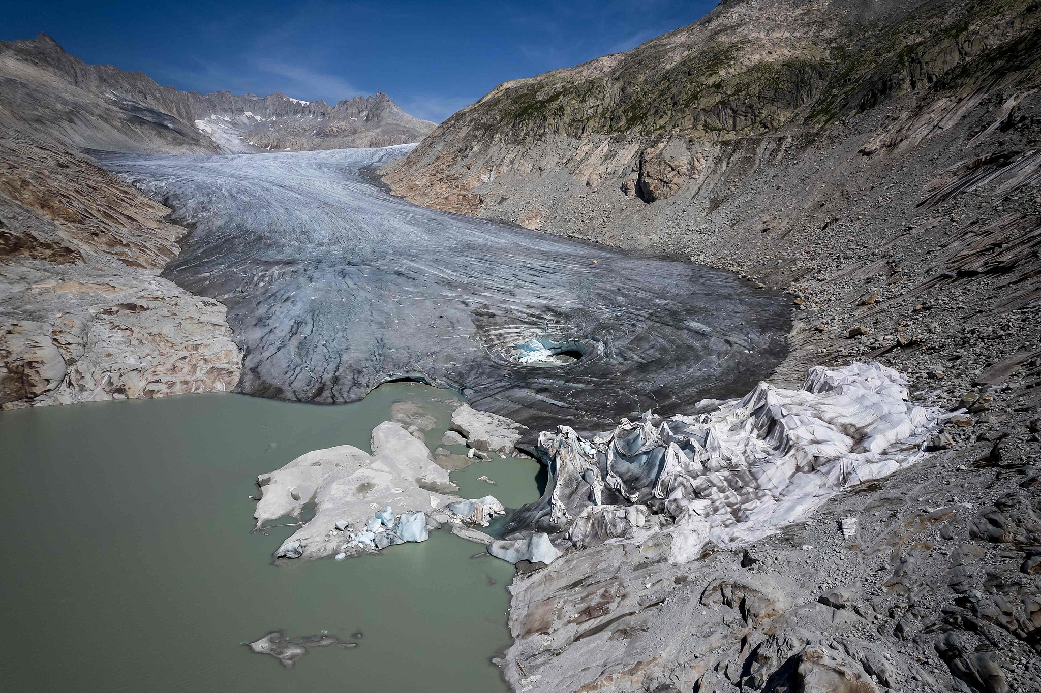 An aerial photograph taken on August 24, 2023 above Gletsch in the Swiss Alps shows insulating foam covering a part of the Rhone Glacier to prevent it from melting, exposing small glacial lakes on its surface due to the ice melting. /CFP