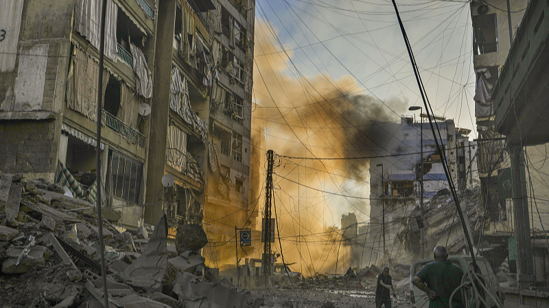 A man runs for cover as a smoke raises in the background following an Israeli airstrike in Dahiyeh, Beirut, Lebanon, October 4, 2024. /CFP