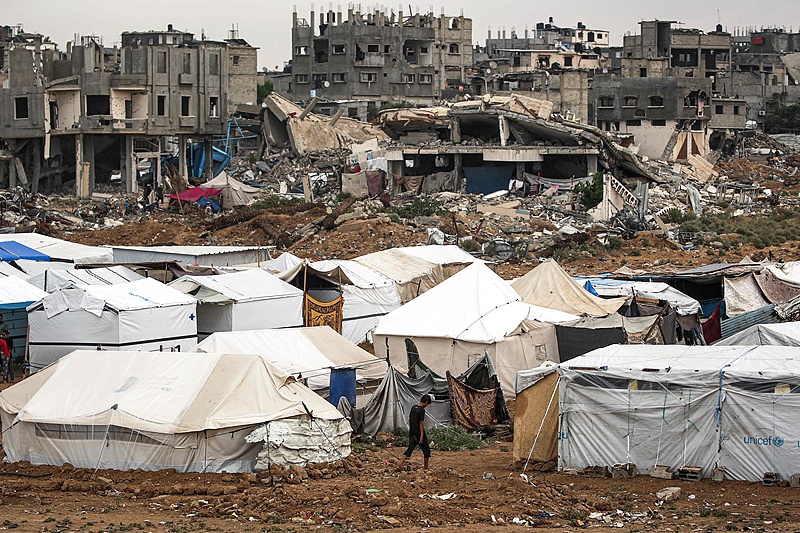 A man walks past shelter tents erected near collapsed buildings in the Bureij camp for Palestinian refugees in the central Gaza Strip, October 1, 2024. /CFP